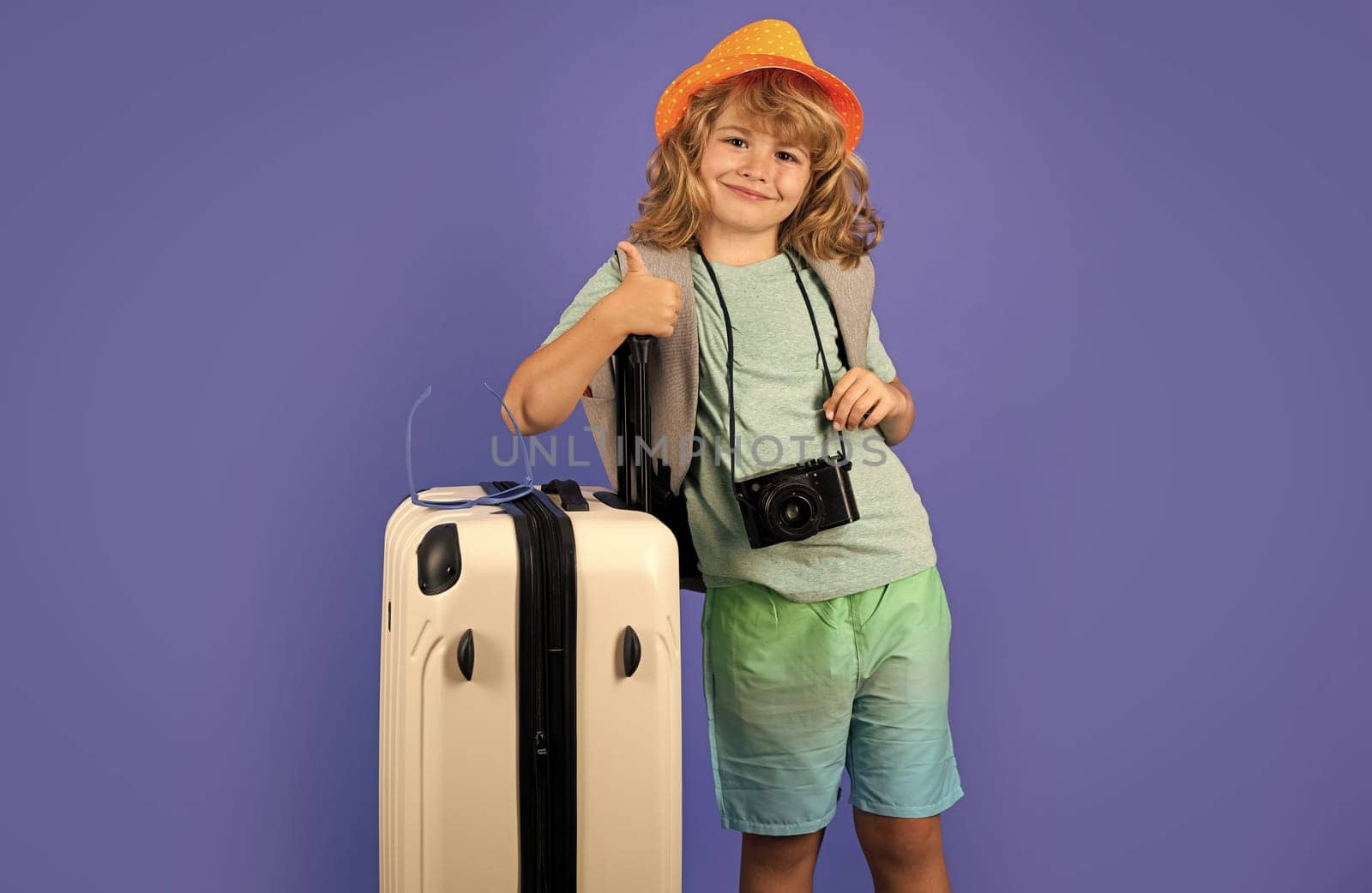 Child traveler with suitcase isolated on studio background. Tourist kid boy. Portrait of child travel with travel bag. Travel, adventure, vacation