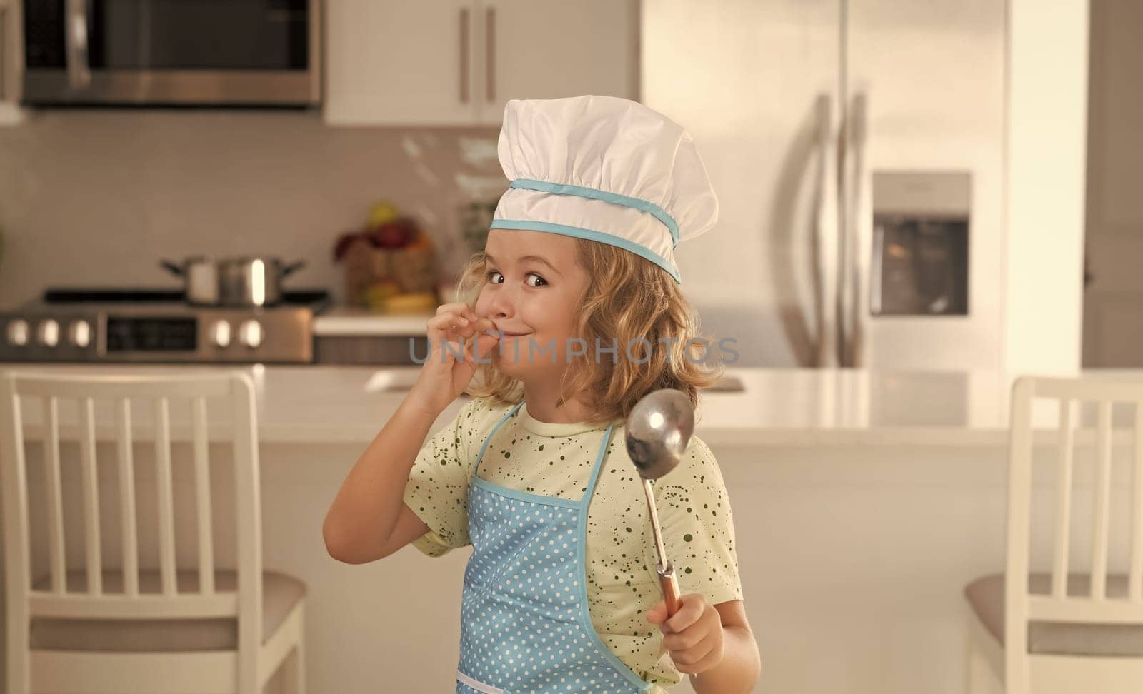 Kid chef cook wearing cooker uniform and chef hat preparing food on kitchen. Cooking, culinary and kids food concept