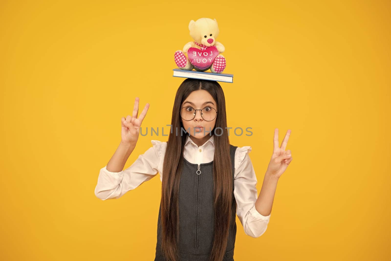 Funny school girl with toy isolated on yellow background. Happy childhood and kids education