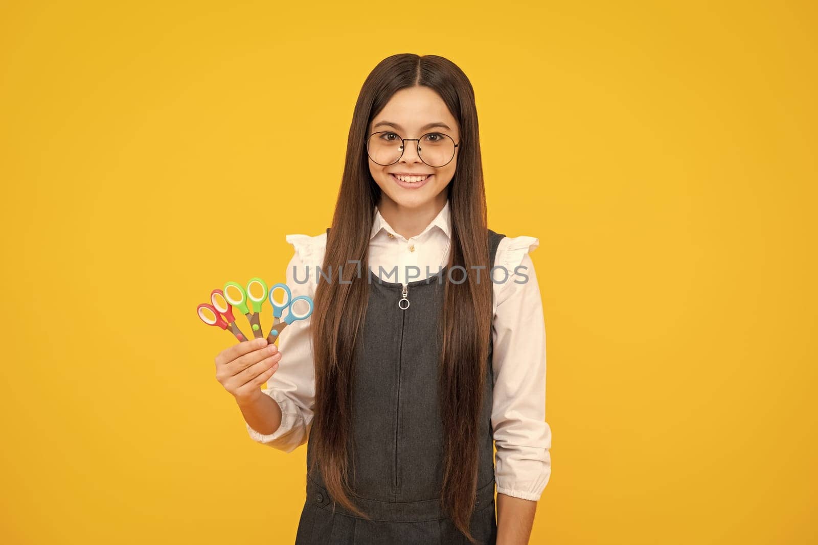 Teenage girl with scissors, isolated on yellow background. Child creativity, arts and crafts