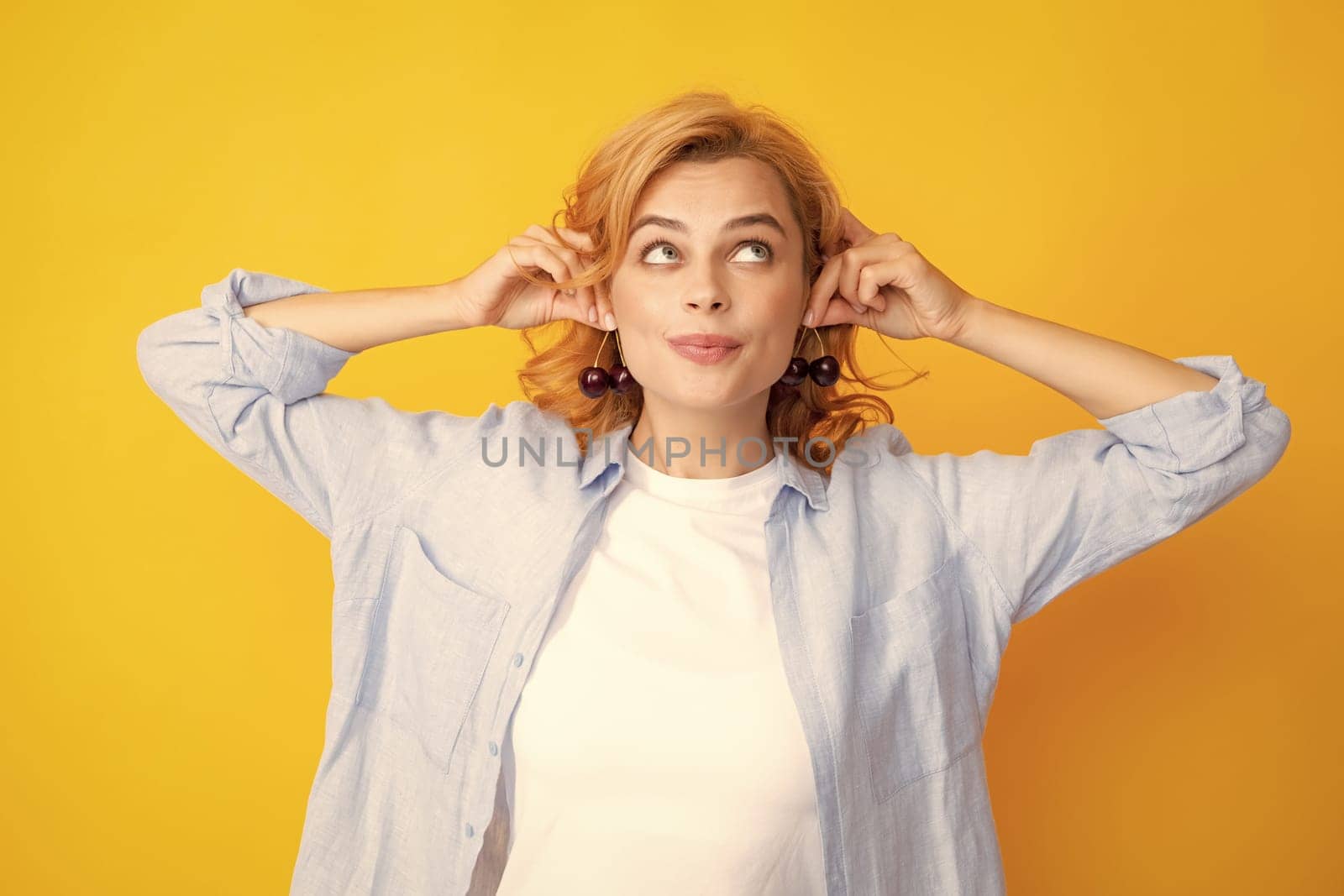 Charming woman with cherry plate isolated on yellow