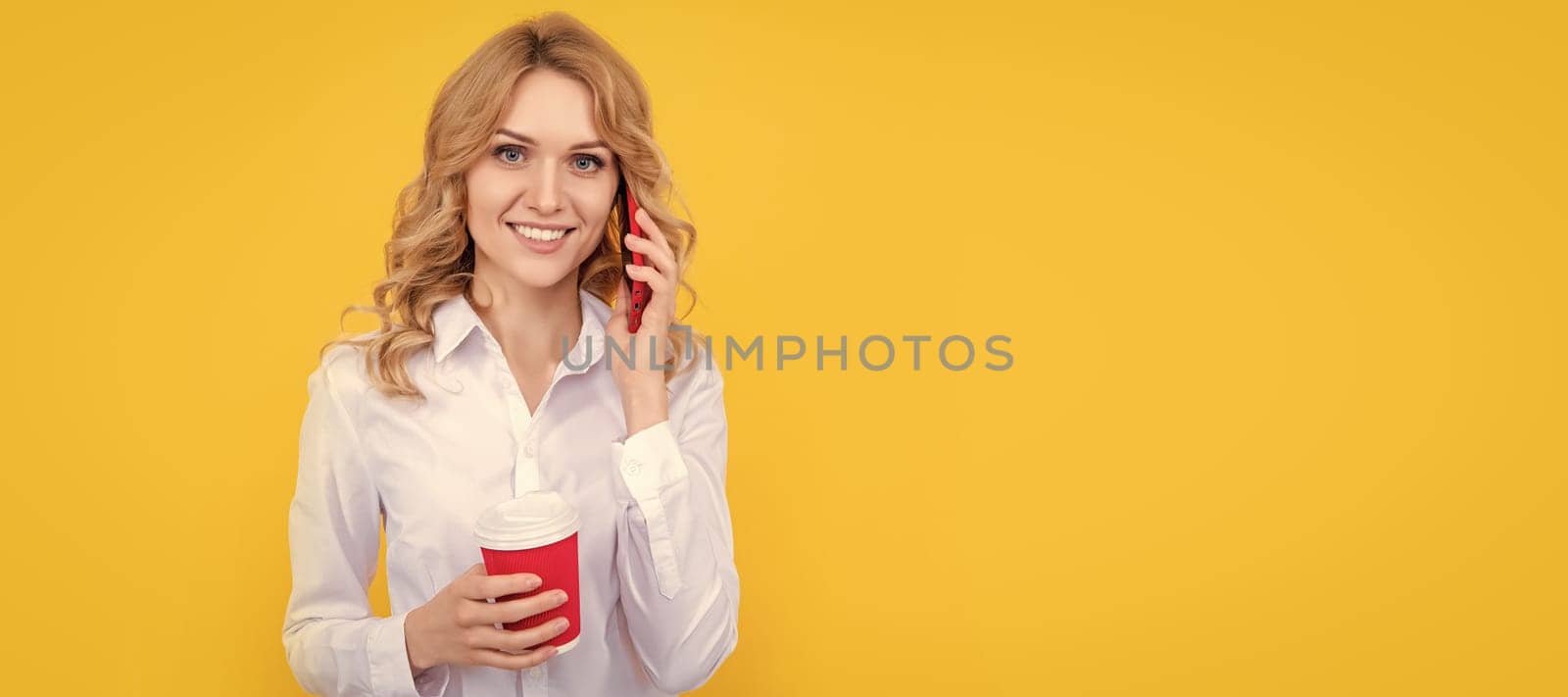 happy blonde woman with coffee cup talking on phone on yellow background. Woman isolated face portrait, banner with mock up copy space. by RedFoxStudio