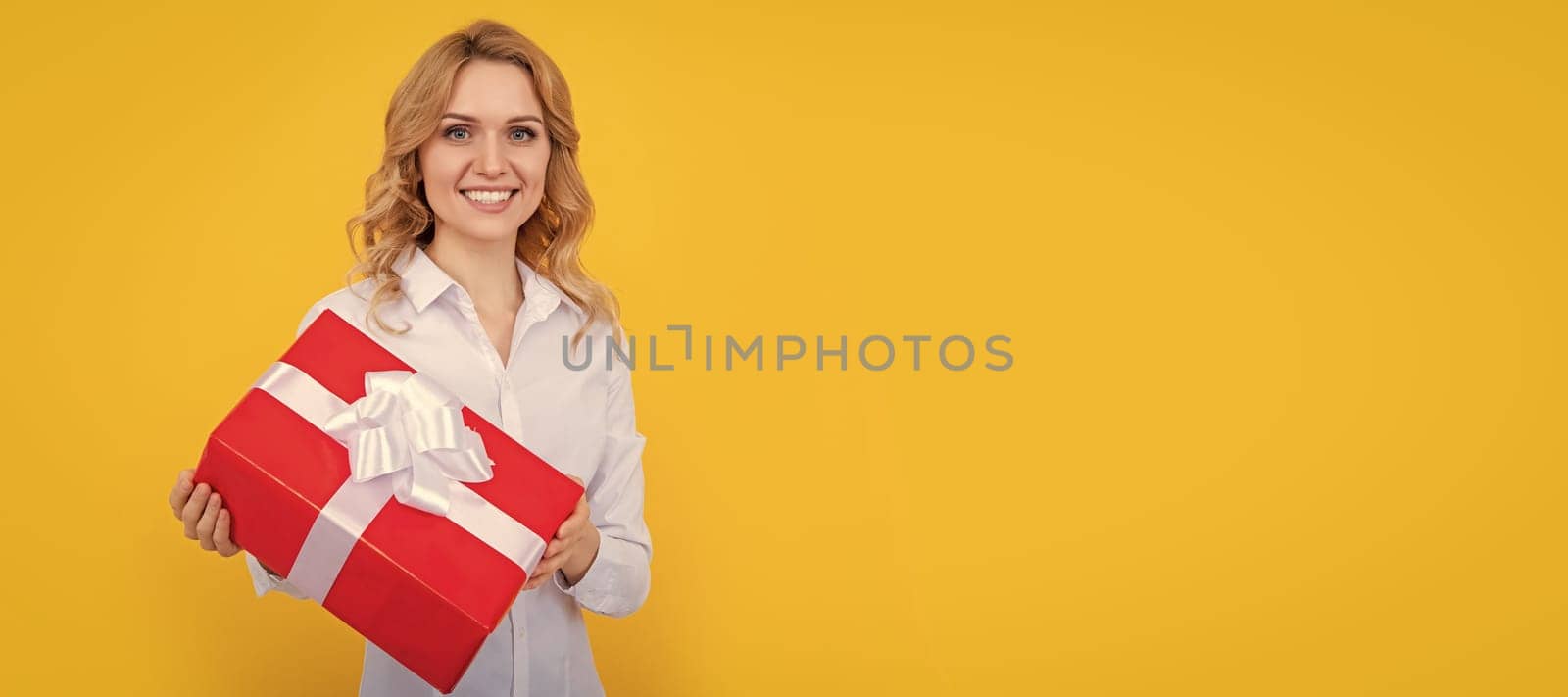 glad woman with big present box on yellow background. Woman isolated face portrait, banner with mock up copy space