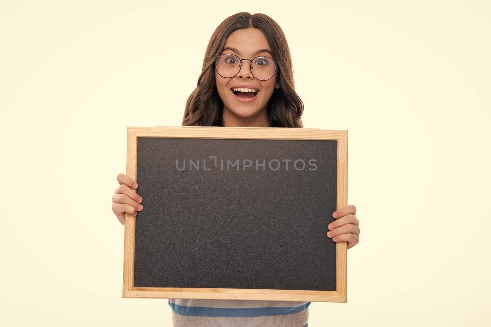 Teenager child holding blank chalkboard for message Isolated on a white studio background. Empty text blackboard, copy space mock up. Happy girl face, positive and smiling emotions