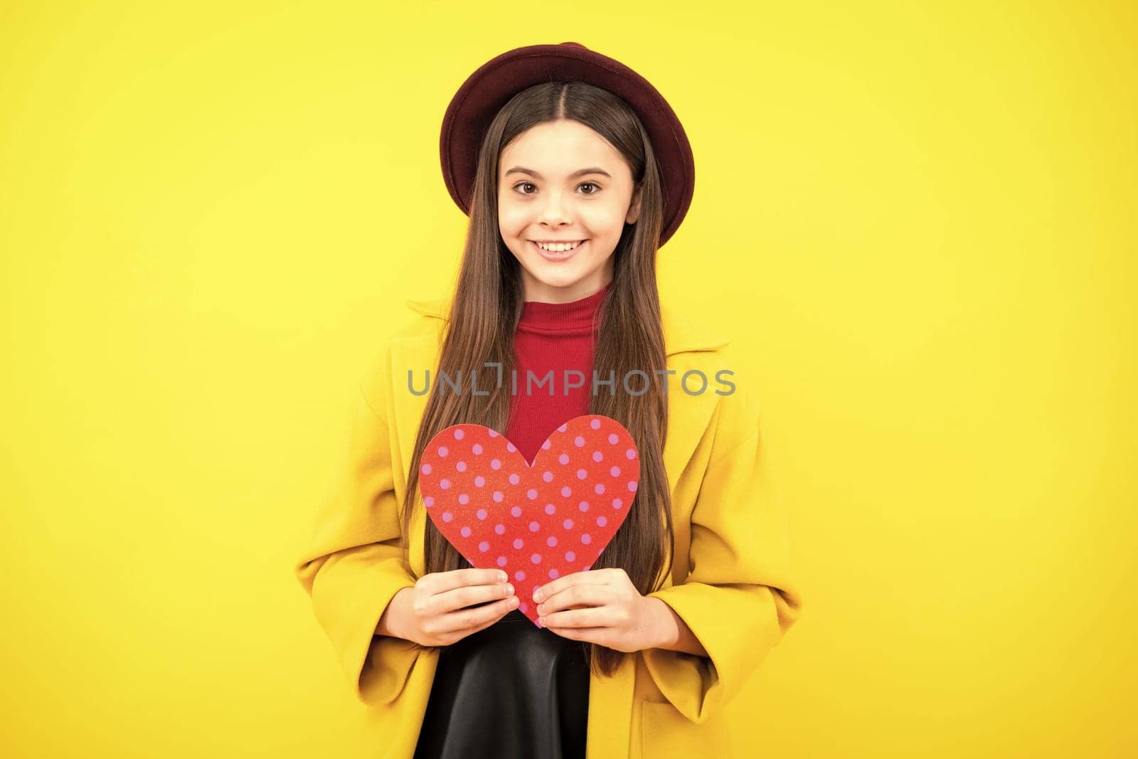 Happy teenager portrait. Young teenager child girl with heart shape. Happy Valentines Day. Love and pleasant feelings concept. Smiling girl