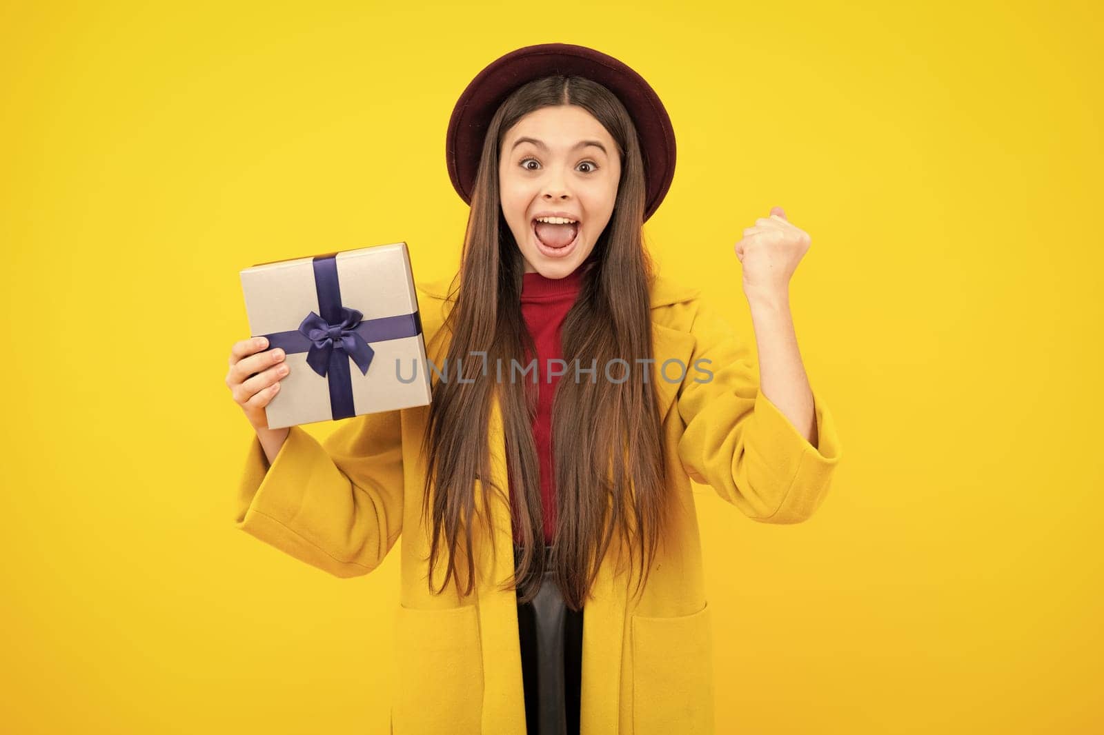 Emotional teenager child hold gift on birthday. Funny kid girl holding gift boxes celebrating happy New Year or Christmas. Excited teenager, glad amazed and overjoyed emotions. by RedFoxStudio