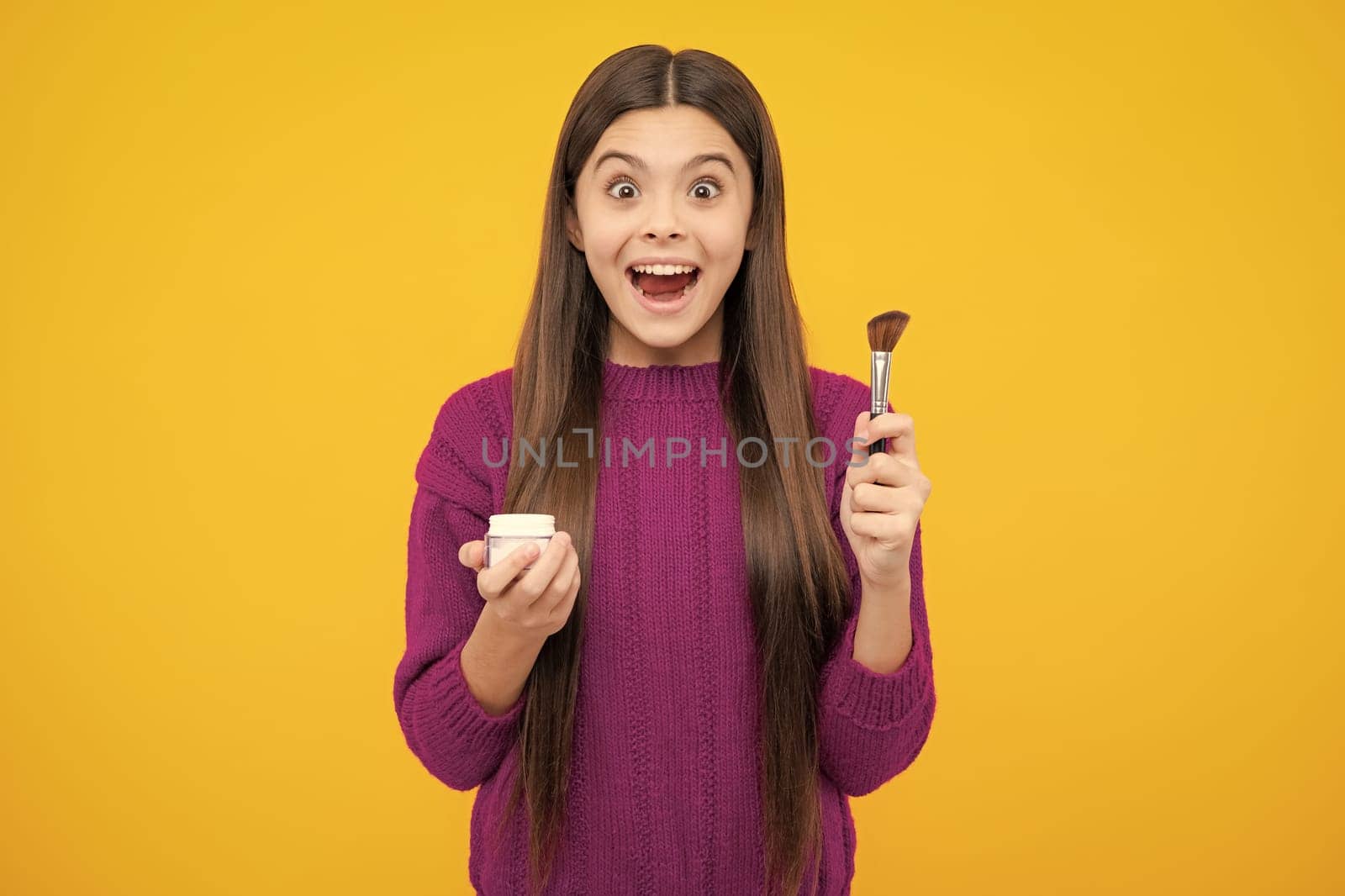 Excited face. Child teen girl making beauty make up, hold powder and brush. Beautiful teenager applying makeup with powder. Amazed expression, cheerful and glad. by RedFoxStudio