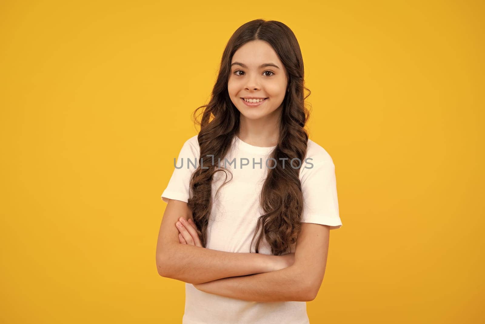 Happy teenager, positive and smiling emotions of teen girl. Portrait of caucasian teen girl with arms folded, isolated on yellow background. Cute teenager child