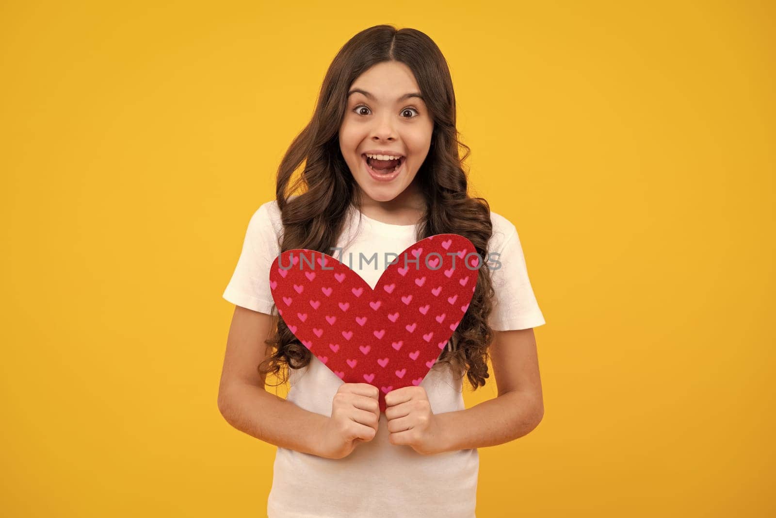 Young teenager child girl with heart shape. Happy Valentines Day. Love and pleasant feelings concept. Happy teenager, positive and smiling emotions of teen girl