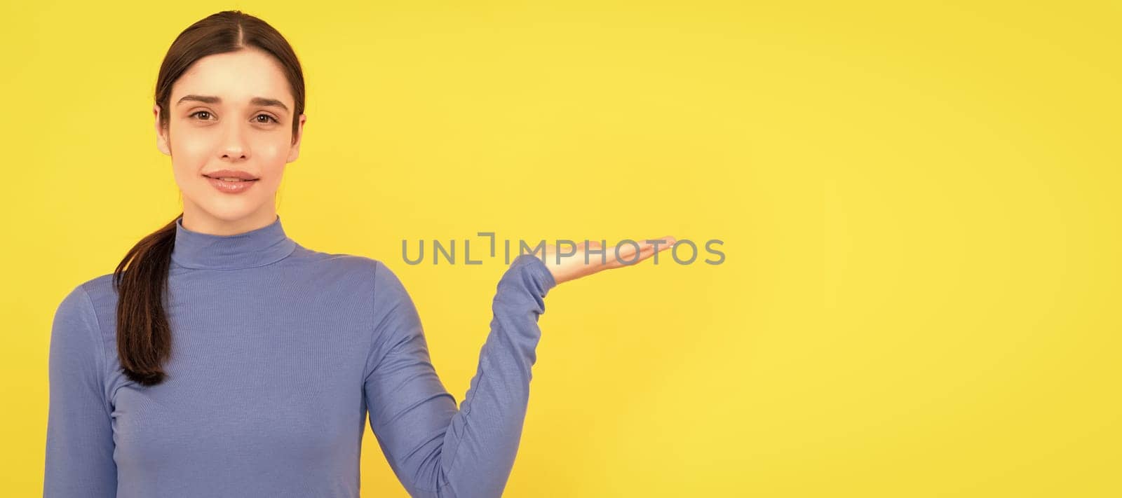 portrait of lady on yellow background. advertisement. woman presenting product. Woman isolated face portrait, banner header poster with mockup copyspace