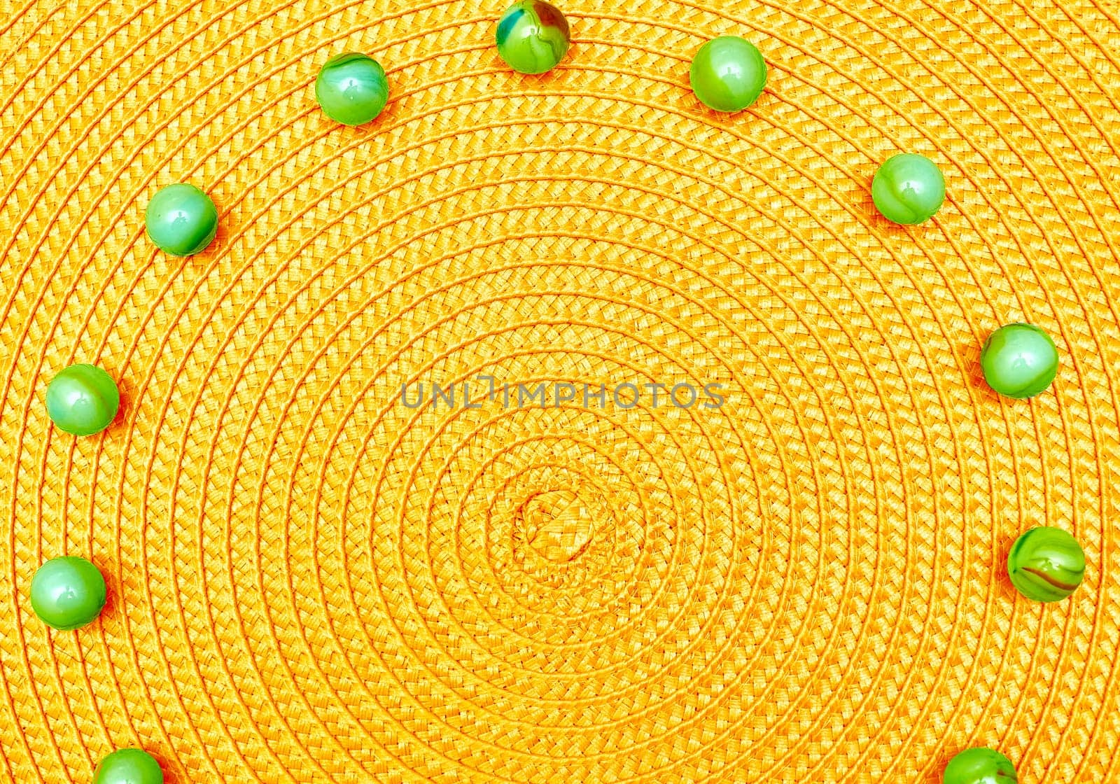 Yellow spiral round straw background with green balls. Place for text by jovani68