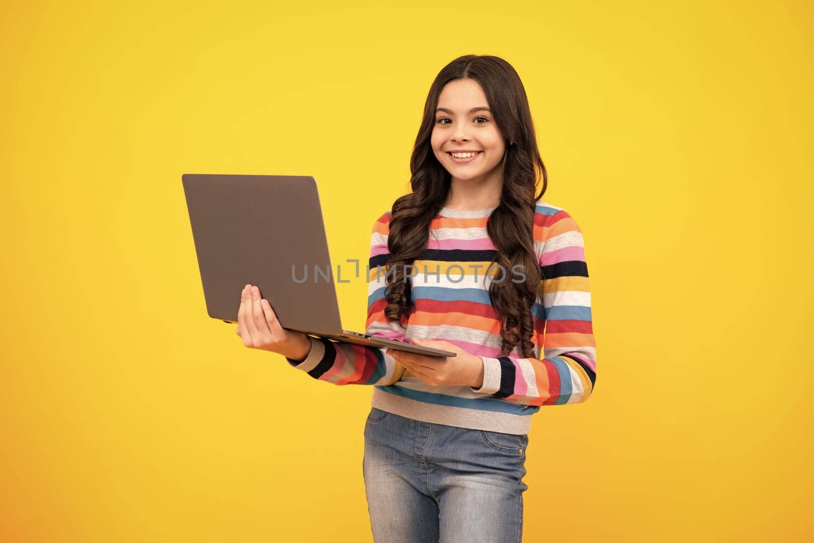 School student using laptop. E-learning and online education. Teen girl on internet video chat isolated on isoalted yellow background. Happy teenager, positive and smiling emotions of teen schoolgirl