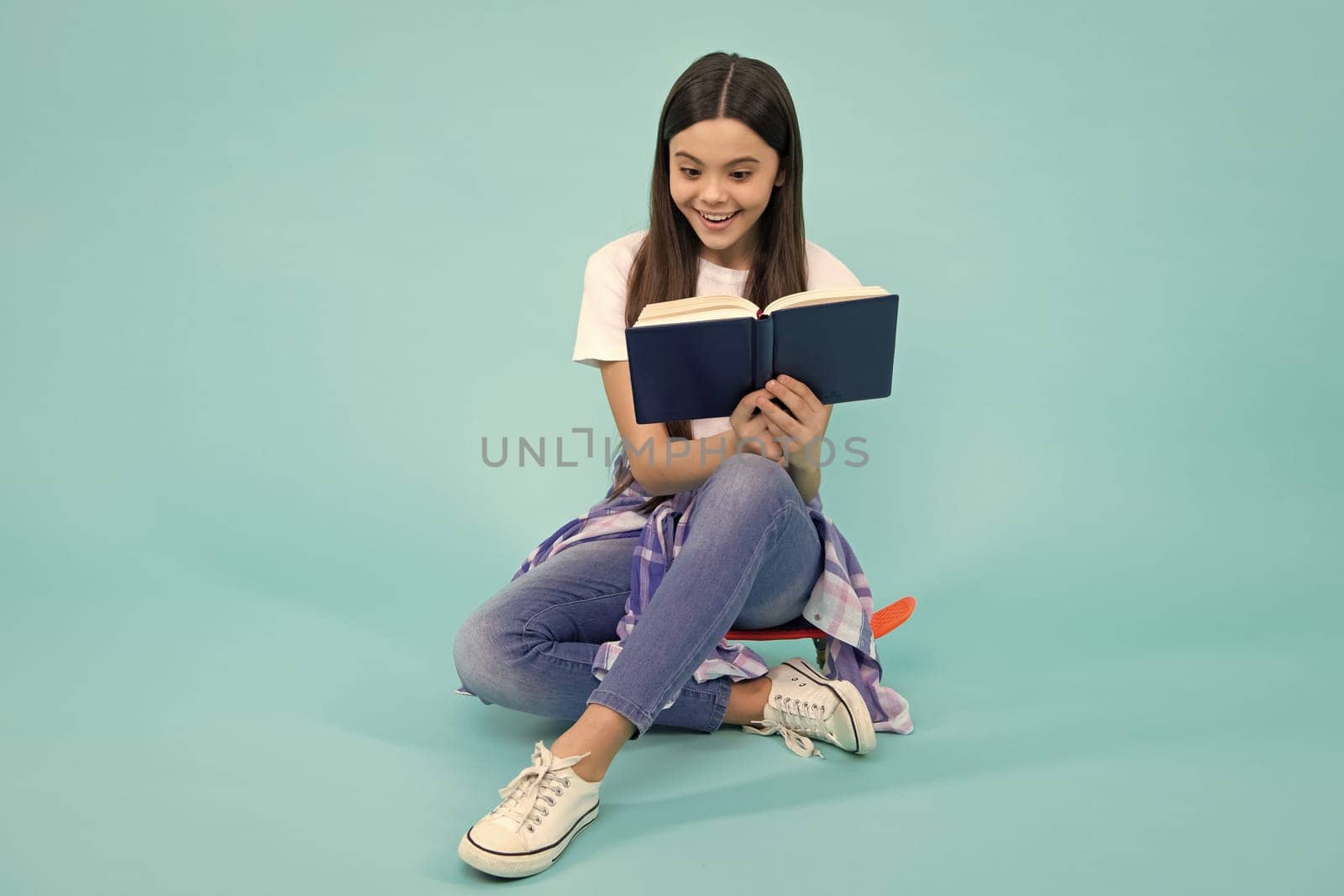 Back to school. Teenager schoolgirl with book ready to learn. School girl children on isolated blue studio background. Happy teenager, positive and smiling emotions of teen girl