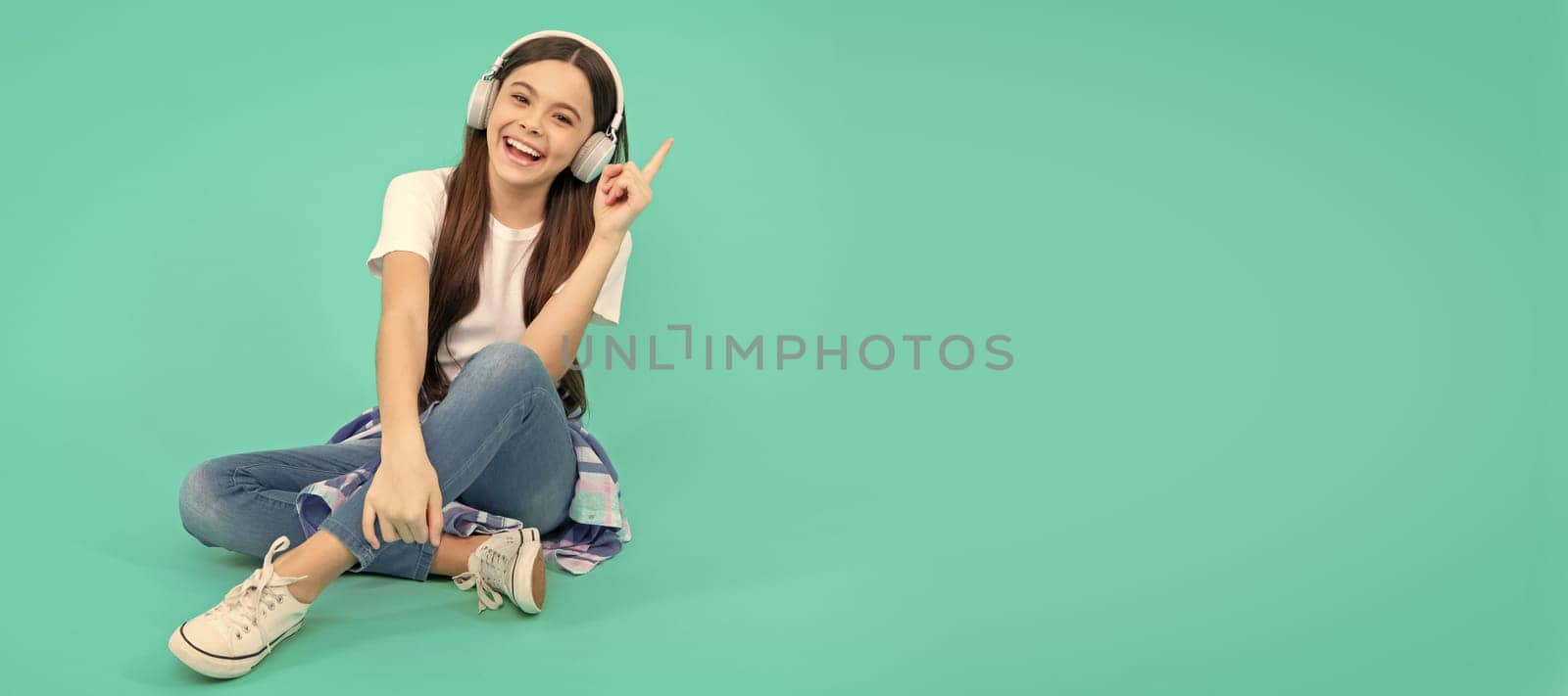 happy teen girl listen to music in wireless headphones. Child portrait with headphones, horizontal poster. Girl listening to music, banner with copy space