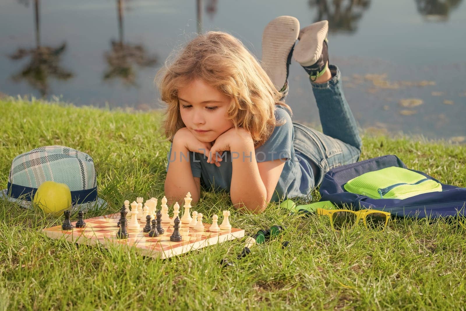 Clever concentrated and thinking child playing chess outdoor in park. by RedFoxStudio