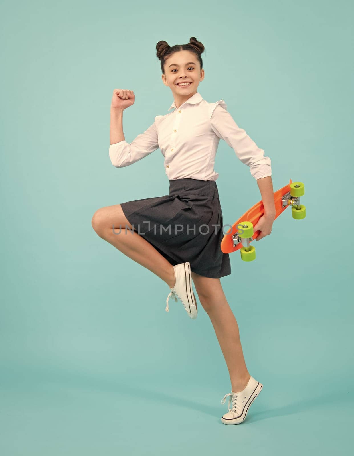 Teen girl 12, 13, 14 years old with skateboard over studio background. Cool modern teenager in stylish clothes. Teenagers lifestyle, casual youth culture
