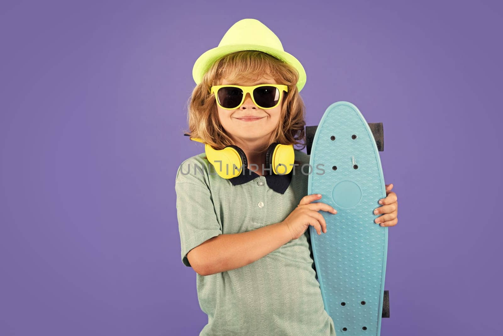 Happy child boy holding skateboard over blue background isolated. Studio portrait of fashion kids. by RedFoxStudio