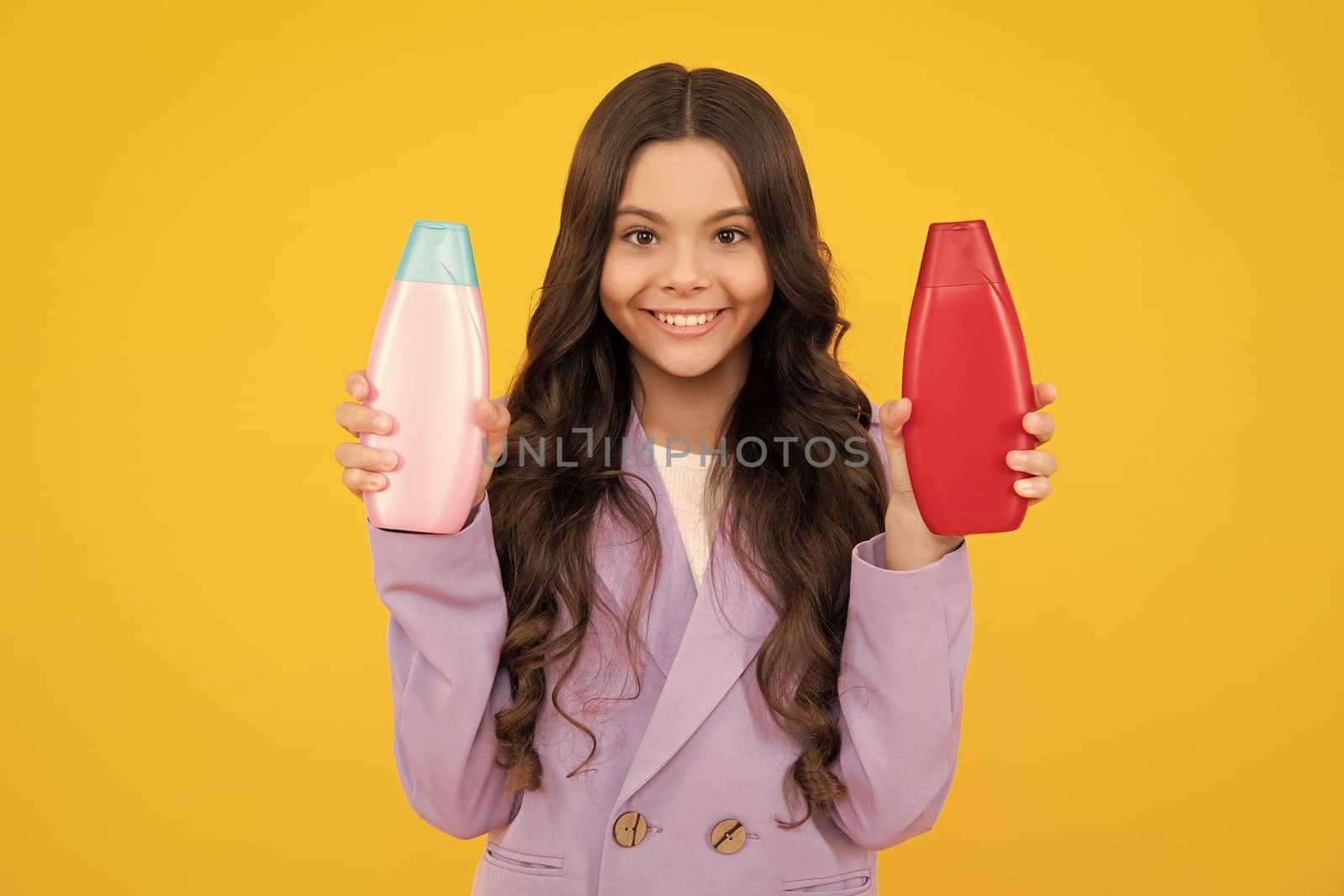 Child with shampoo conditioner. Daily cosmetic care. Teenager hold bottle of hair and skin care. Beauty health and cosmetics. Happy teenager, positive and smiling emotions of teen girl. by RedFoxStudio