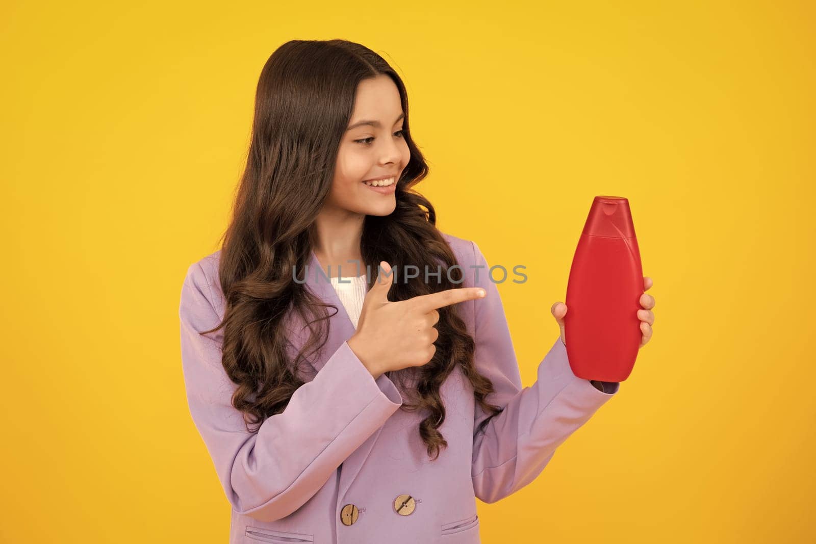 Child teen girl with shampoos conditioners and shower gel. Long hair care of teenager. Presenting cosmetic product, shampoo bottle. Happy teenager, positive and smiling emotions of teen girl