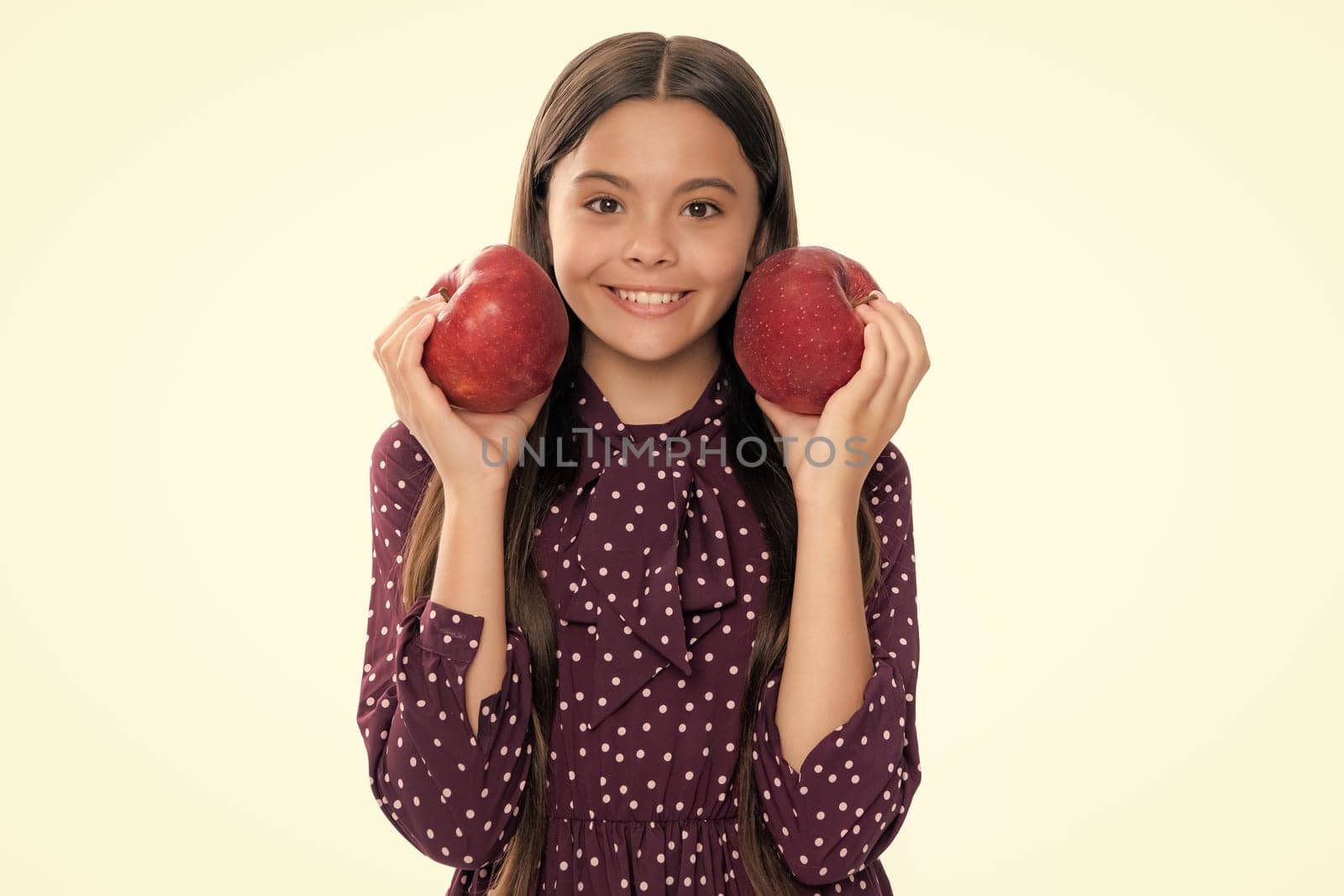 Child girl eating an apple over isolated white studio background. Tennager with fruit. Portrait of happy funny smiling teenage child girl