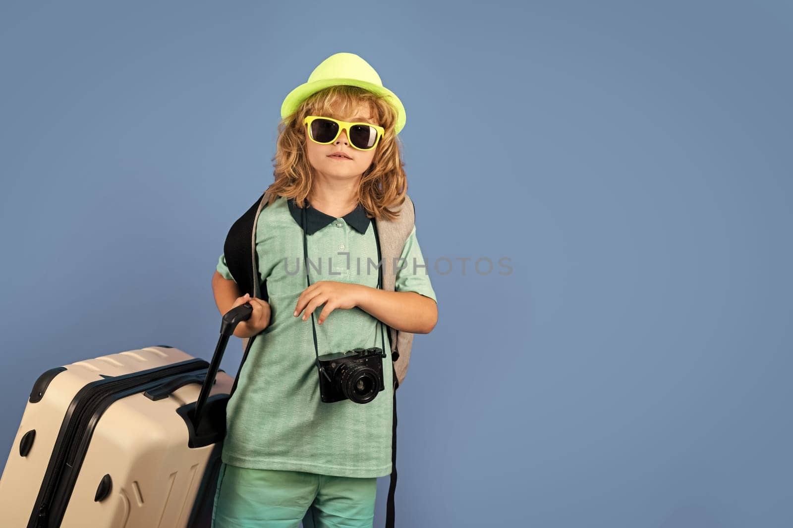 Child traveler with suitcase isolated on studio background. Tourist kid boy. Portrait of child travel with travel bag. Travel, adventure, vacation