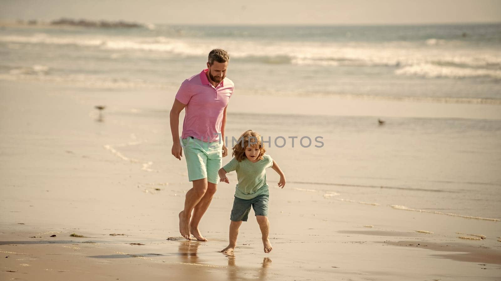 family of daddy man and child boy running on beach together, childhood.