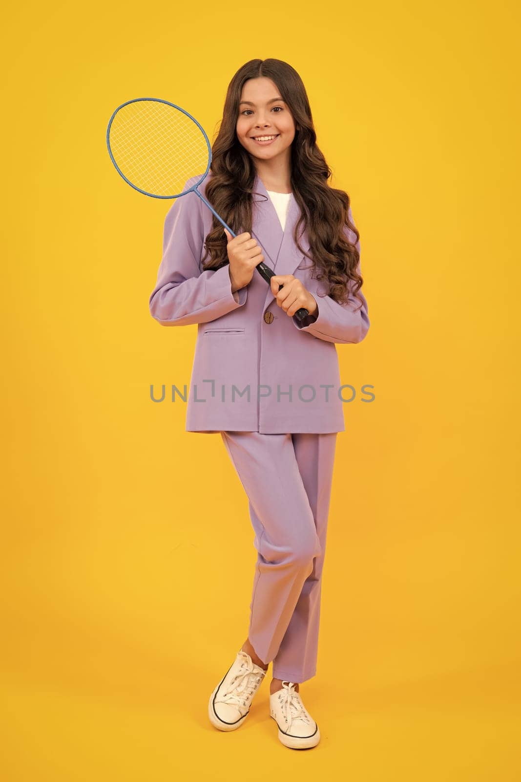 Teen girl badminton player in suit with badminton racket isolated on yellow background. by RedFoxStudio