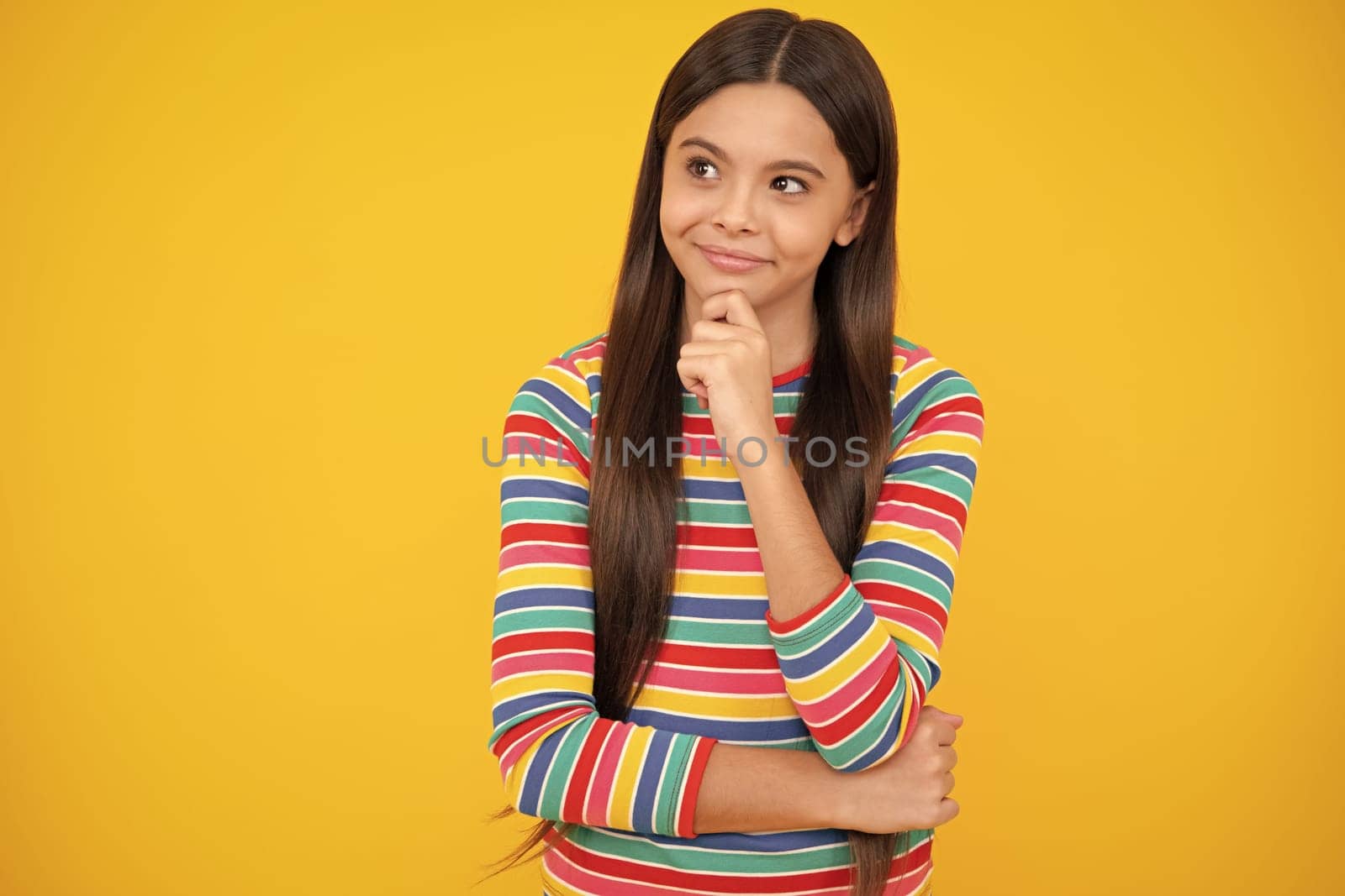 Funny face. Teenager girl 12, 13, 14 years old thinking against yellow background. Child think and creative idea concept