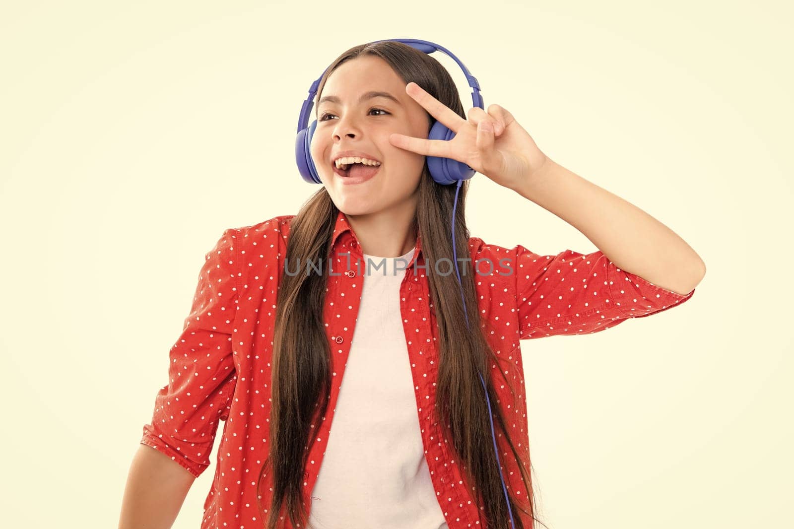 Young teen child listening music with headphones. Girl listening songs via wireless headphones. Wireless headset device accessory. Portrait of emotional amazed excited teen girl. by RedFoxStudio