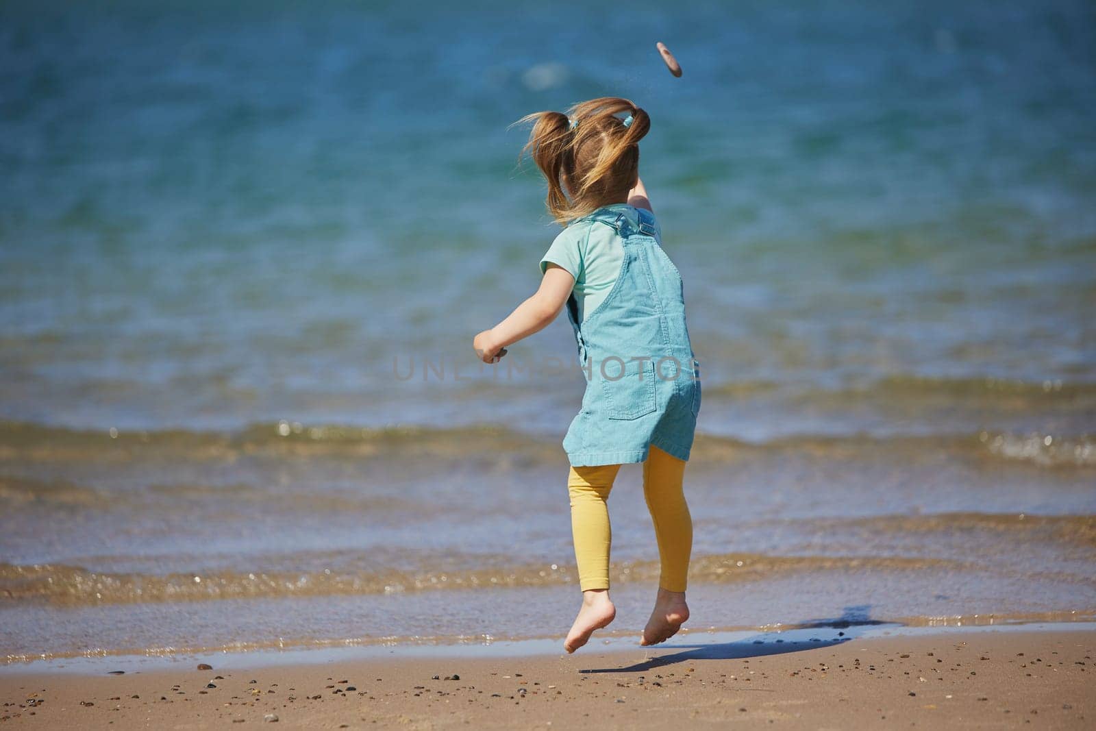 Charming child throws a stone into the sea in Denmark.