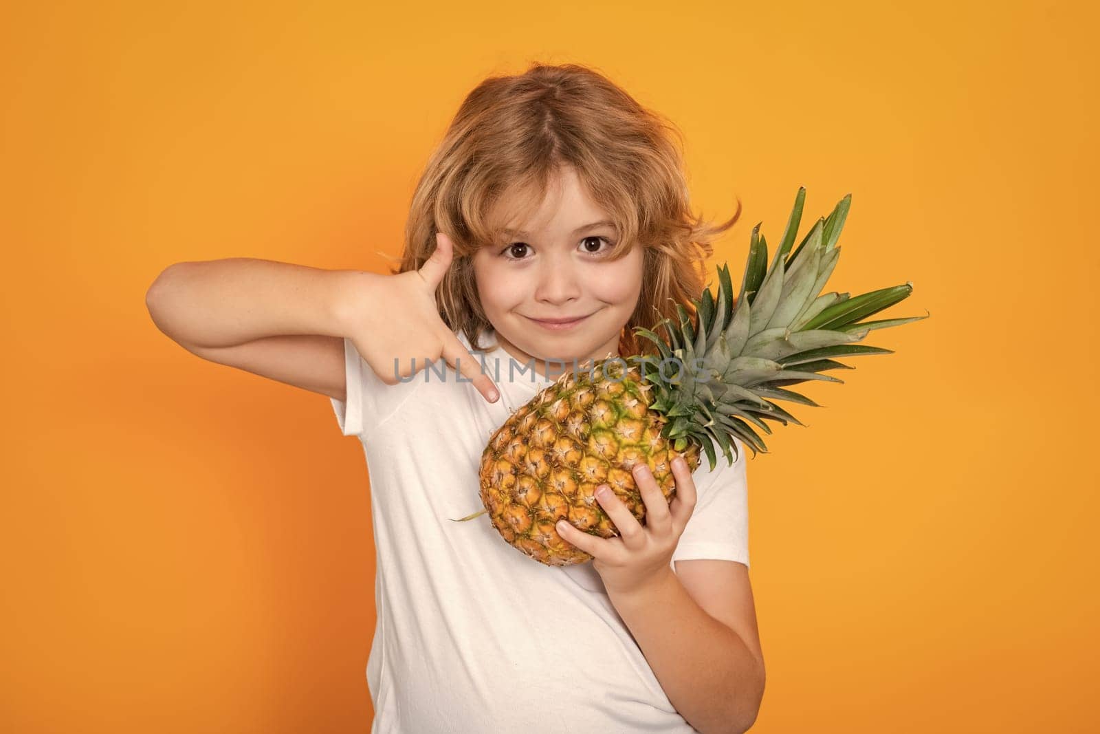 Kid with pineapple in studio. Studio portrait of cute child hold pineapple isolated on yellow background