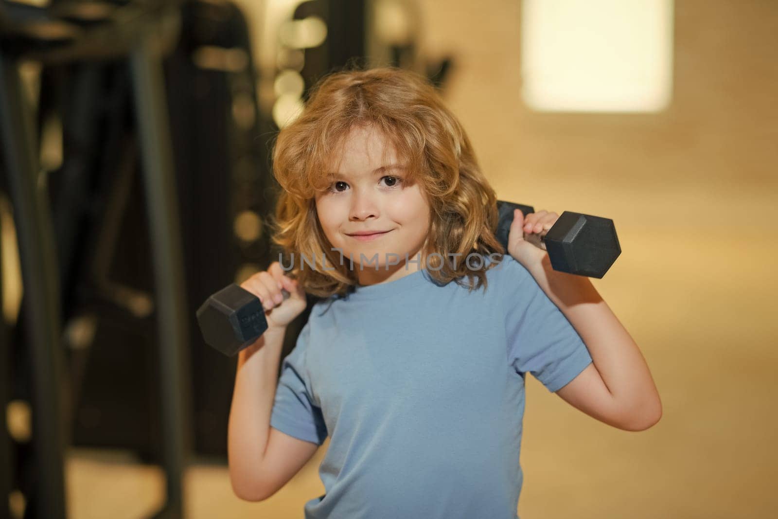 Sport activities at leisure with children. Boy holding dumbbells. by RedFoxStudio