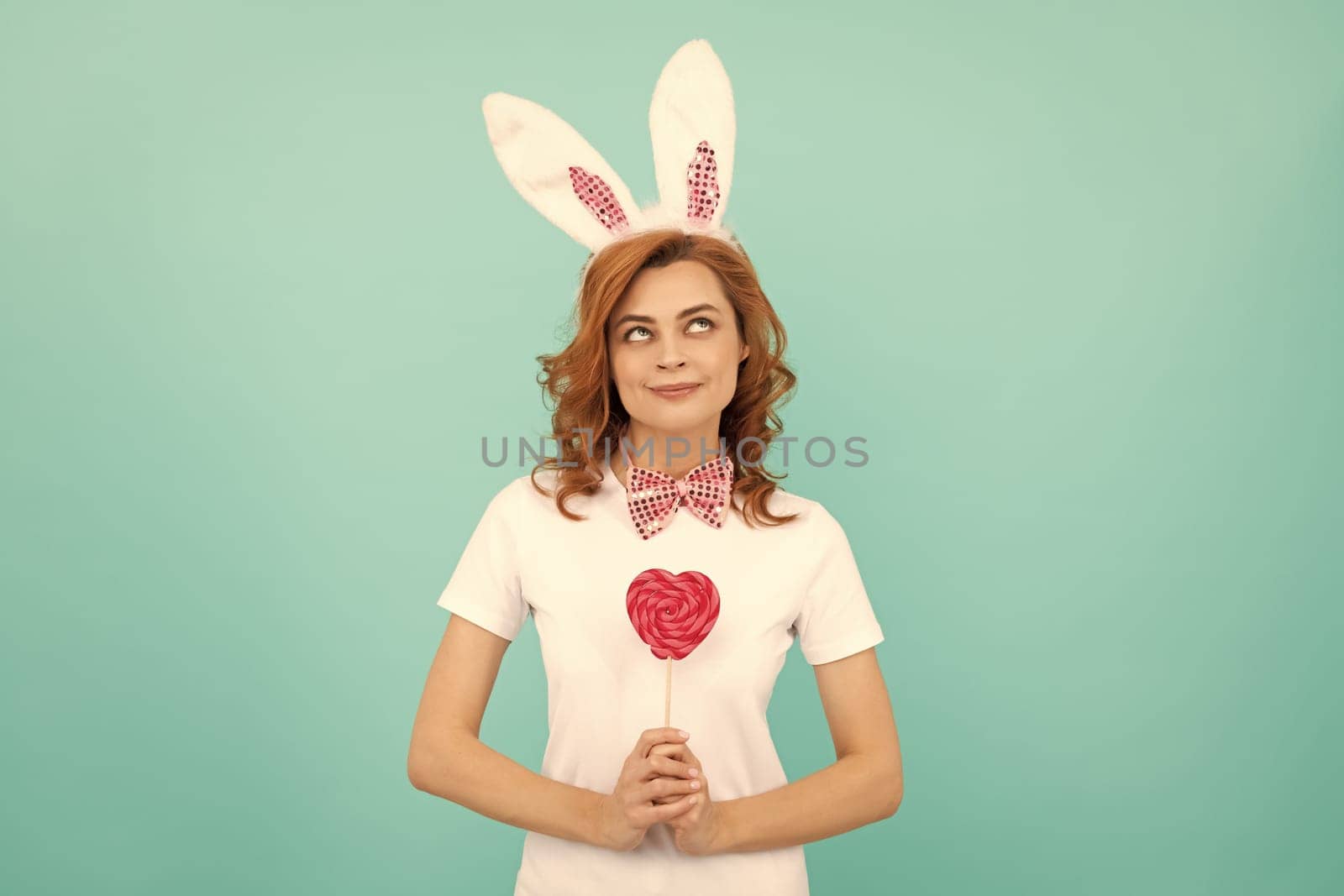 cheerful easter girl wear bunny ears hold heart lollipop.