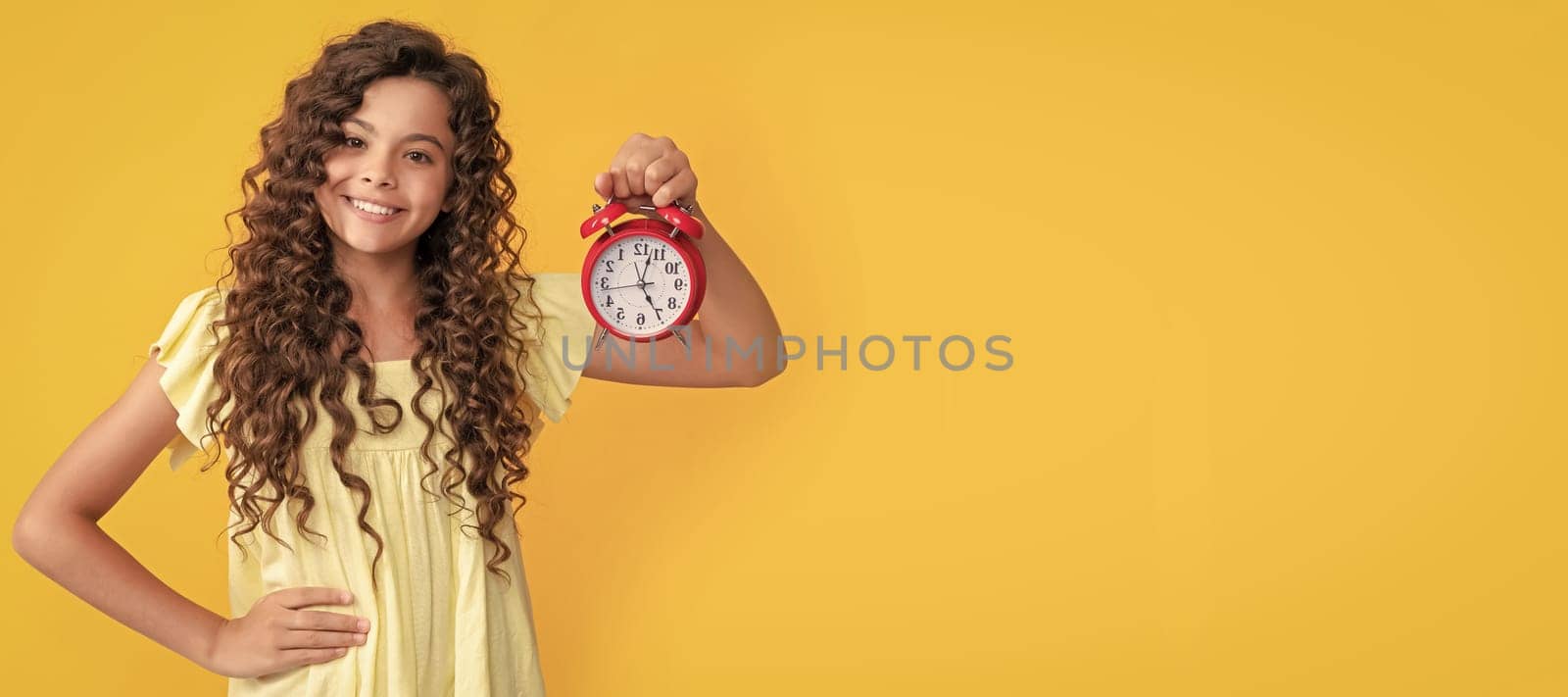 cheerful child with alarm clock. school kid curly hair showing clock. you are late. deadline. Teenager child with clock alarm, horizontal poster. Banner header, copy space