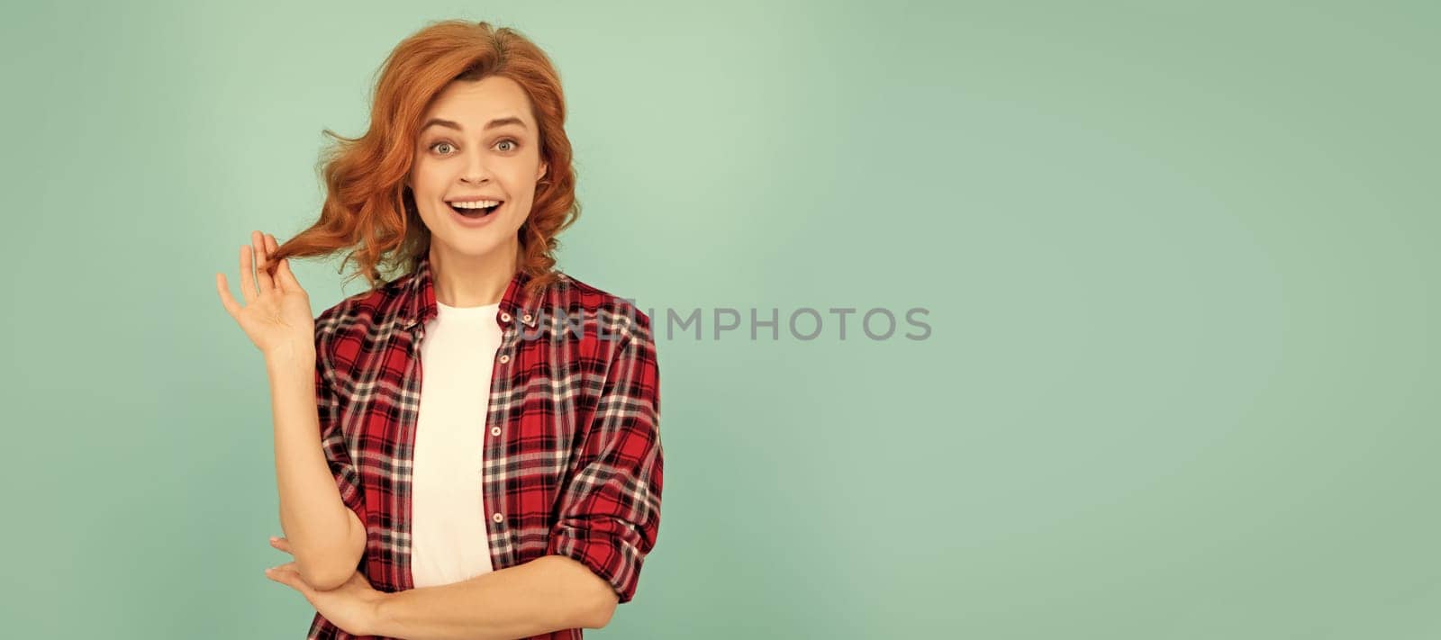 amazed redhead girl in checkered shirt on blue background. Woman isolated face portrait, banner with mock up copyspace. by RedFoxStudio