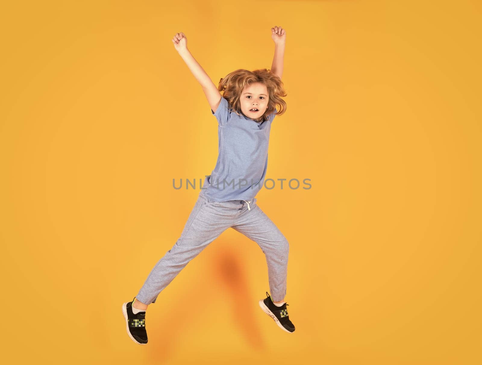 Boy jumping. Full size of kid boy have fun jump up isolated over yellow background. by RedFoxStudio
