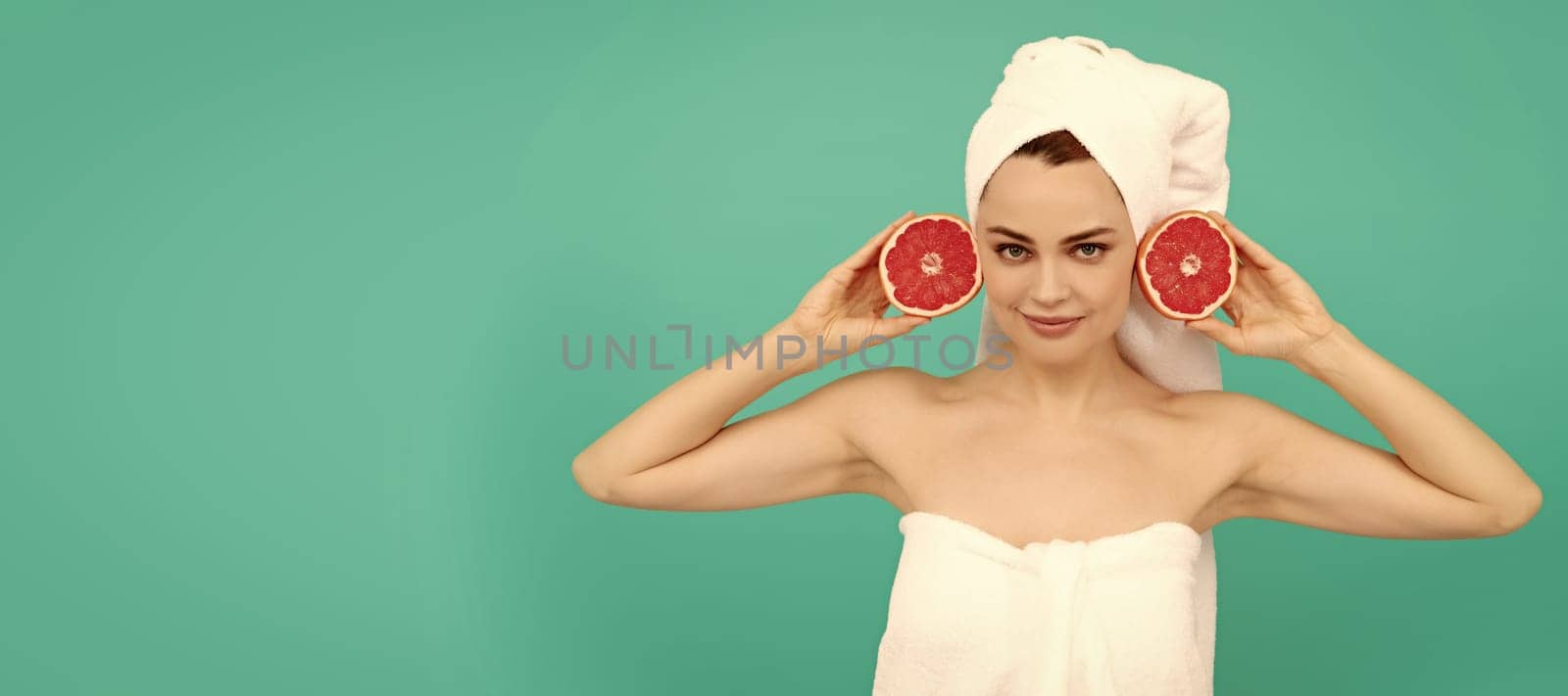 young woman in towel after shower with grapefruit on blue background. vitamin c. Beautiful woman isolated face portrait, banner with mock up copy space