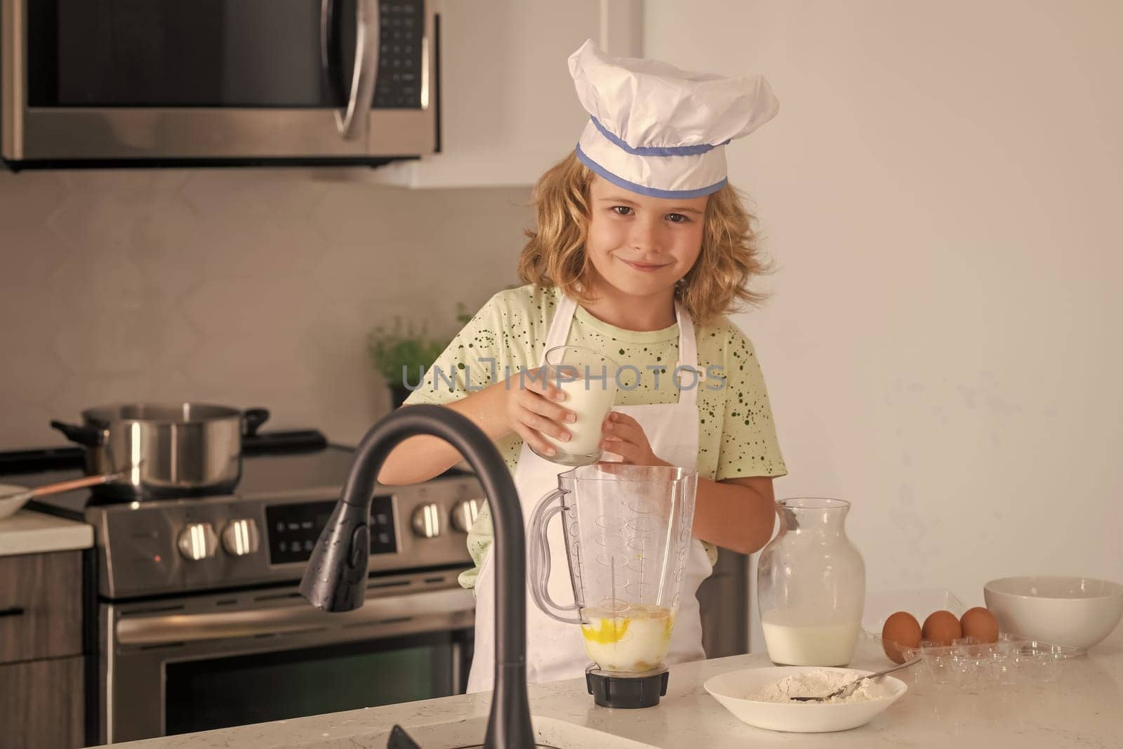 Children cooking in the kitchen. Funny kid chef cook cookery at kitchen. Chef kid boy making healthy food. Portrait of little child in chef hat