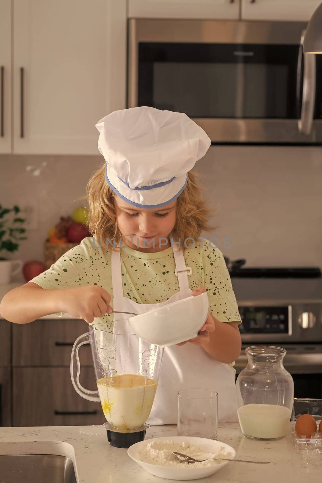 Children cooking in the kitchen. Funny kid chef cook cookery at kitchen. Chef kid boy making healthy food. Portrait of little child in chef hat. by RedFoxStudio