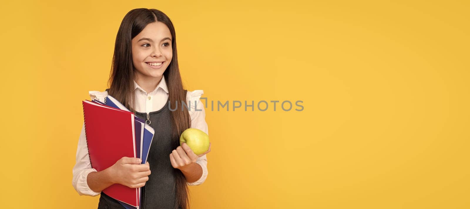 Happy girl child back to school holding apple and books yellow background, knowledge day. Banner of school girl student. Schoolgirl pupil portrait with copy space. by RedFoxStudio