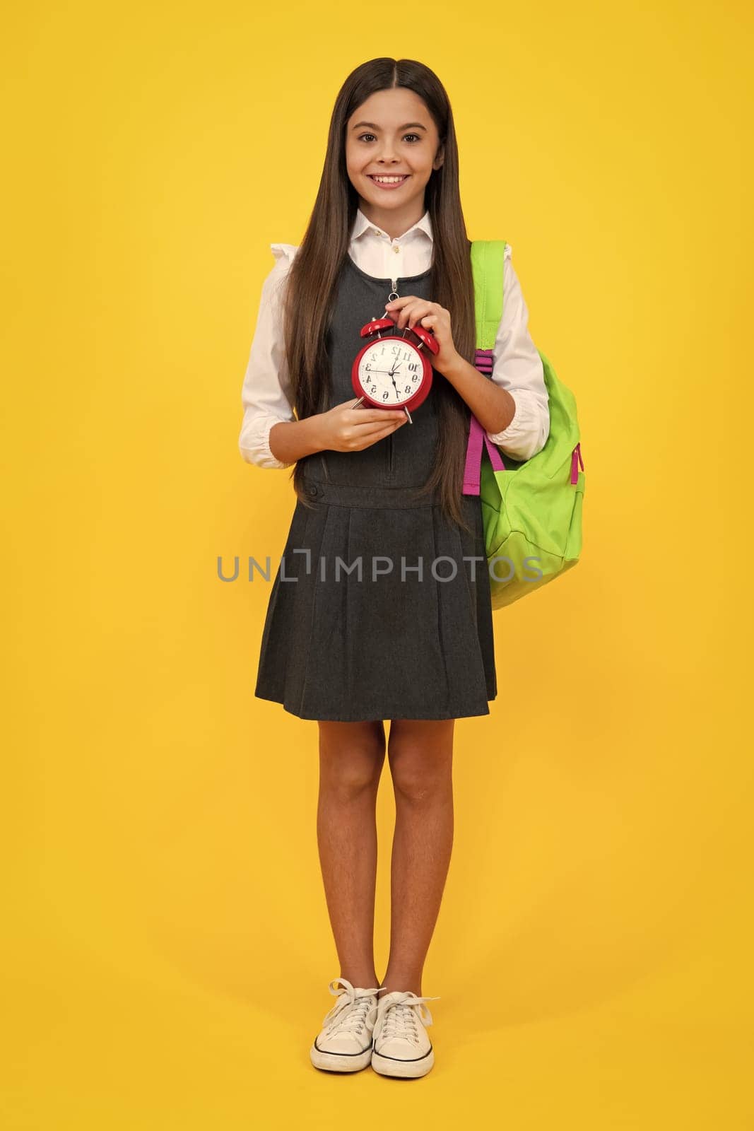 School and education concept. Back to school. Schoolchild, teenage student girl with clock alarm, time to study. Happy girl face, positive and smiling emotions