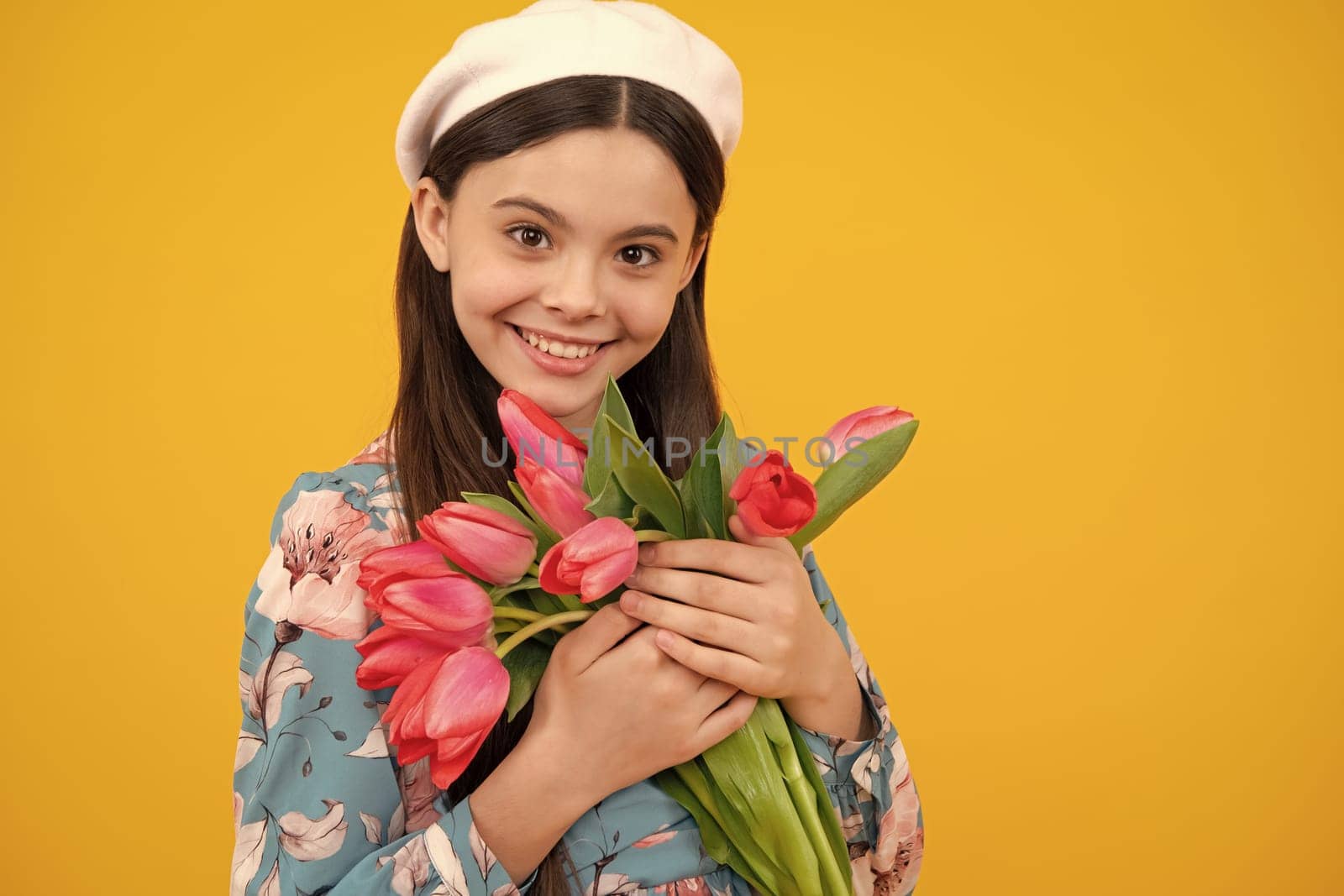 Happy teenager girl in beret hat hold spring tulip flowers on yellow background. Child with spring tulips bouquet, floral present. by RedFoxStudio