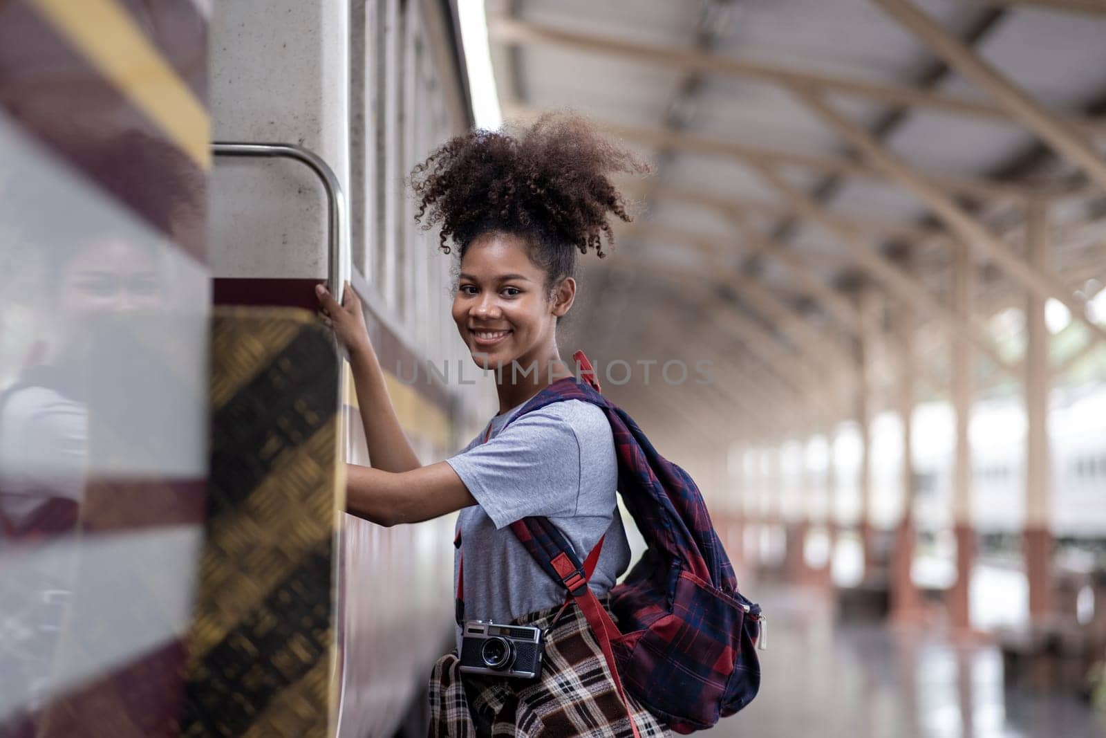 Traveler African Asian American woman getting in a train to hop on train, Young woman female standing on train door peeking out looking from door, tourist on a train station. High quality photo