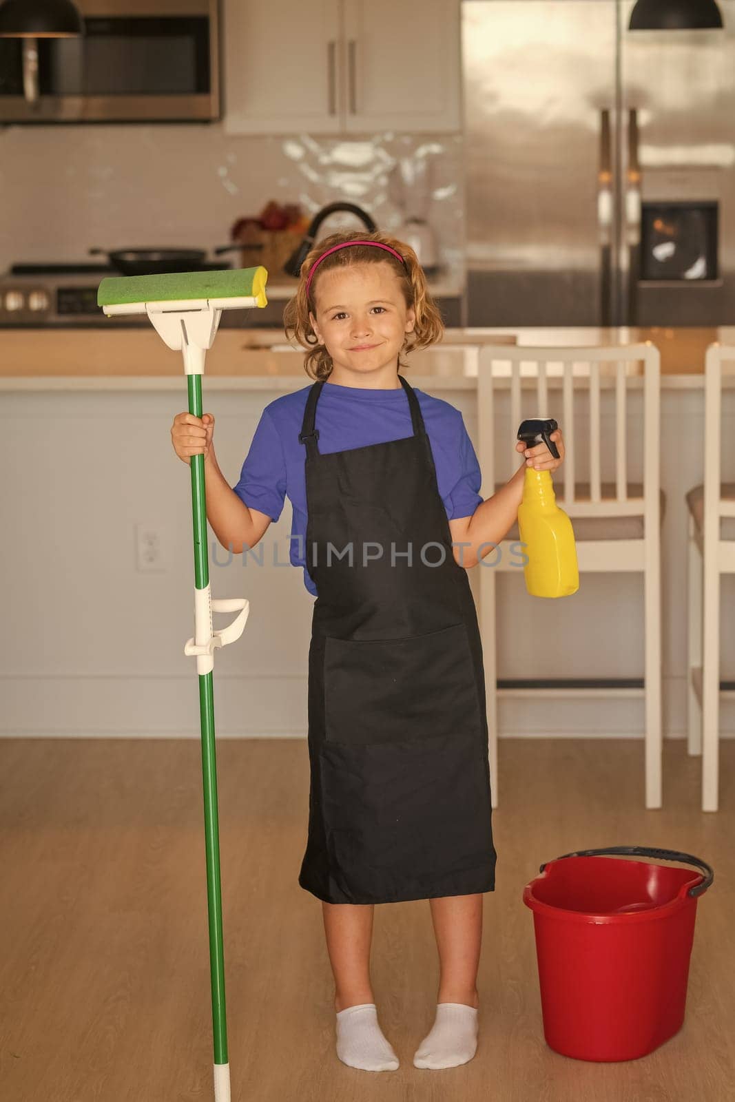 Child use duster and gloves for cleaning. Funny child mopping house. Cleaning accessory, cleaning supplies. Housekeeping and home cleaning