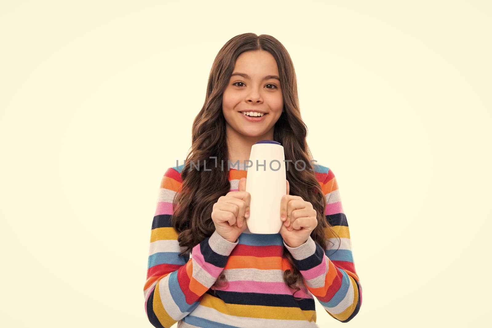 Teenager child girl showing bottle shampoo conditioners or shower gel isolated on white background. Hair cosmetic product. Mock up bottle. Happy girl face, positive and smiling emotions