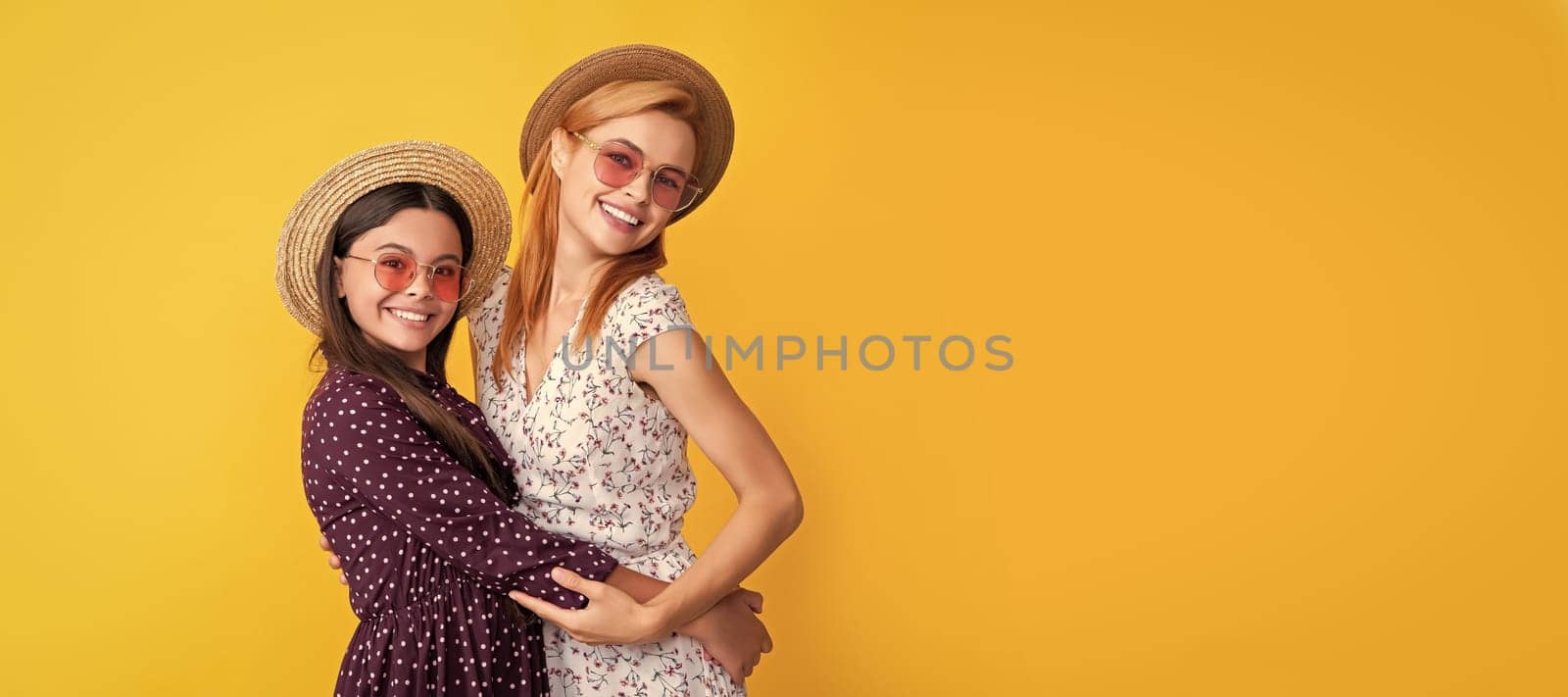 Mother and daughter kid banner, copy space, isolated background. mom and daughter smile in straw hat on yellow background