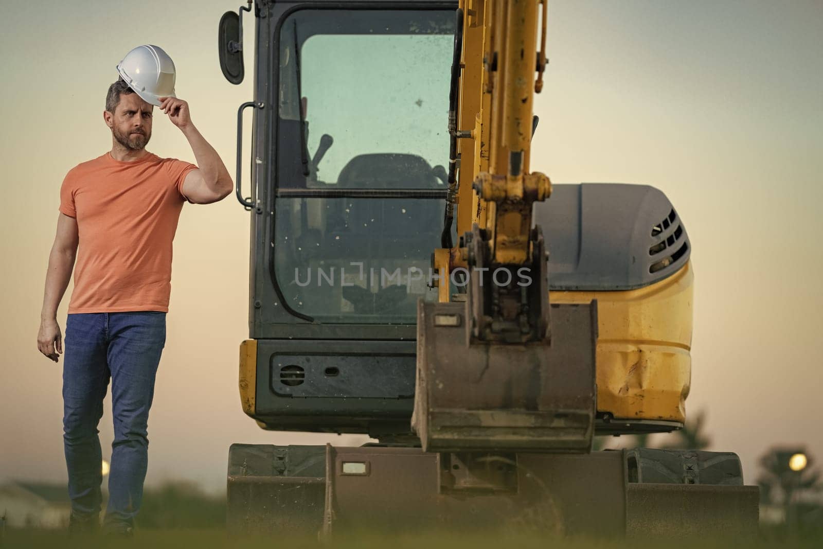 Worker with bulldozer on site construction. Man excavator worker. Construction driver worker with excavator on the background. Construction worker with tractor or construction vehicle at building. by RedFoxStudio