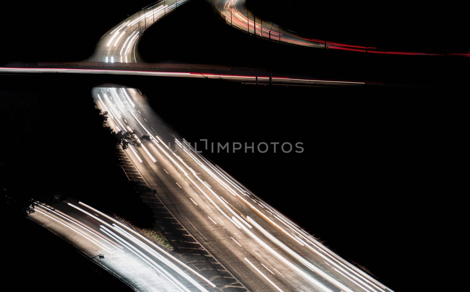 Long exposure night view of a highway with car lights creating blurred motion. The image features a lot of traffic, multiple lanes, and a dark black space for text. .