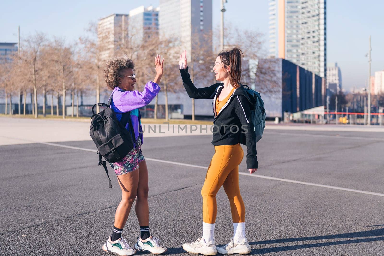 two happy sportswomen shaking hands before running in the city, concept of friendship and sportive lifestyle