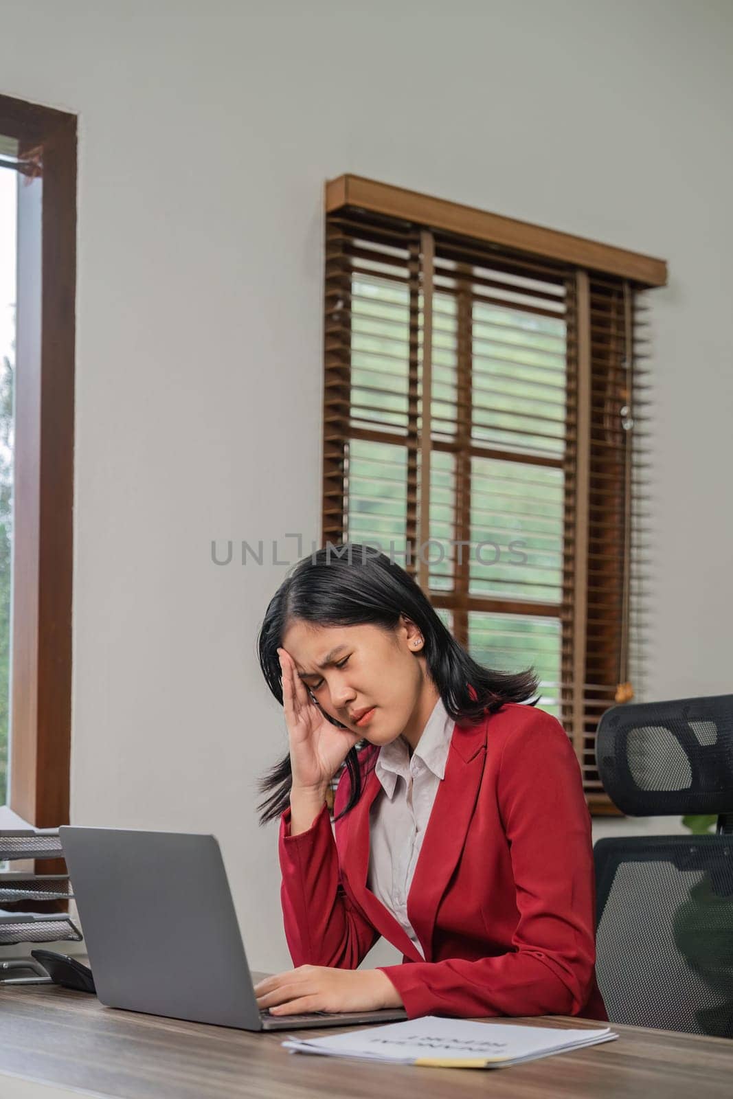 Exhausted businesswoman having a headache in modern office. business woman working at office desk with on head feeling tired. Stressed casual business woman feeling eye pain.